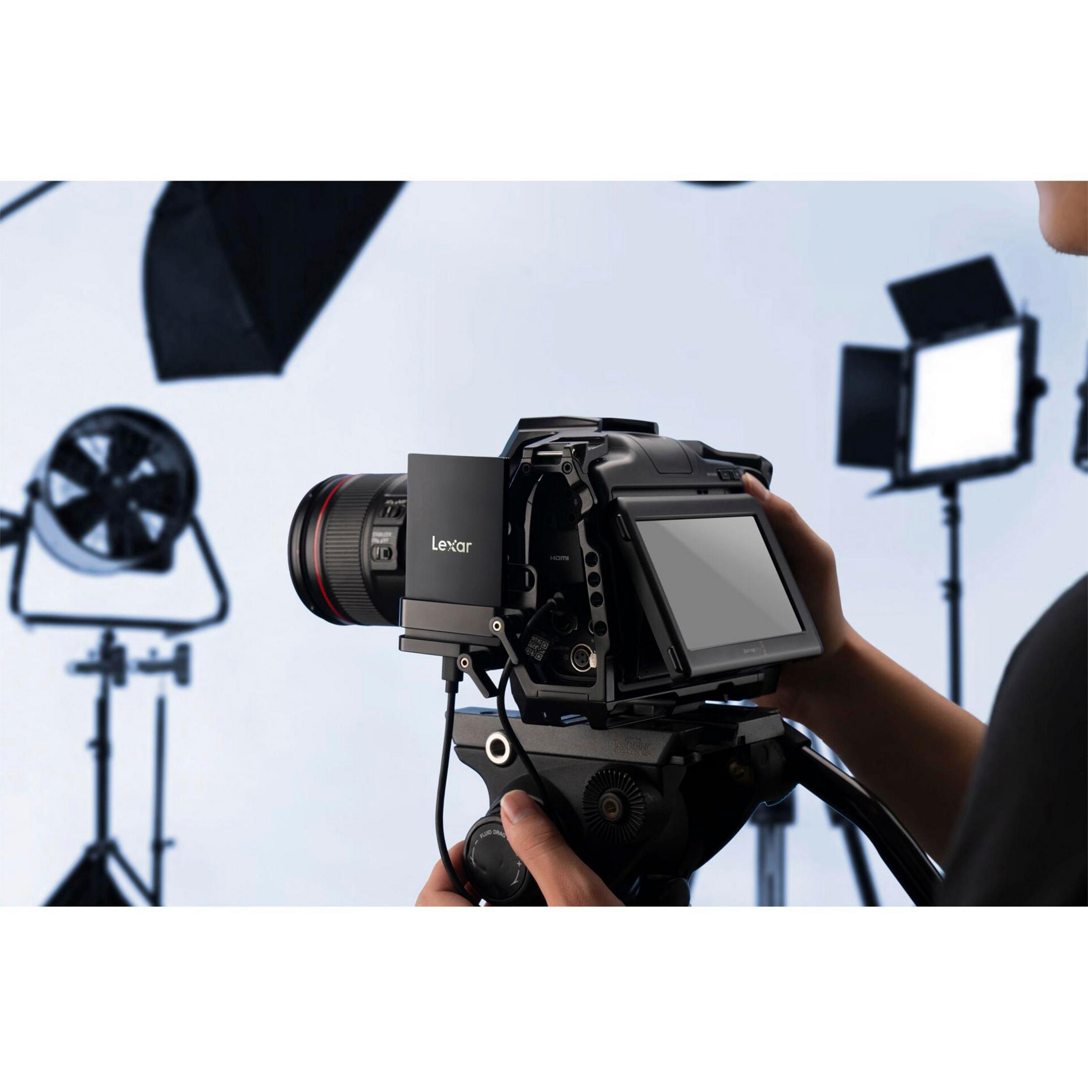Una persona tiene una telecamera professionale con unità Lexar collegata. Luci da studio sullo sfondo.