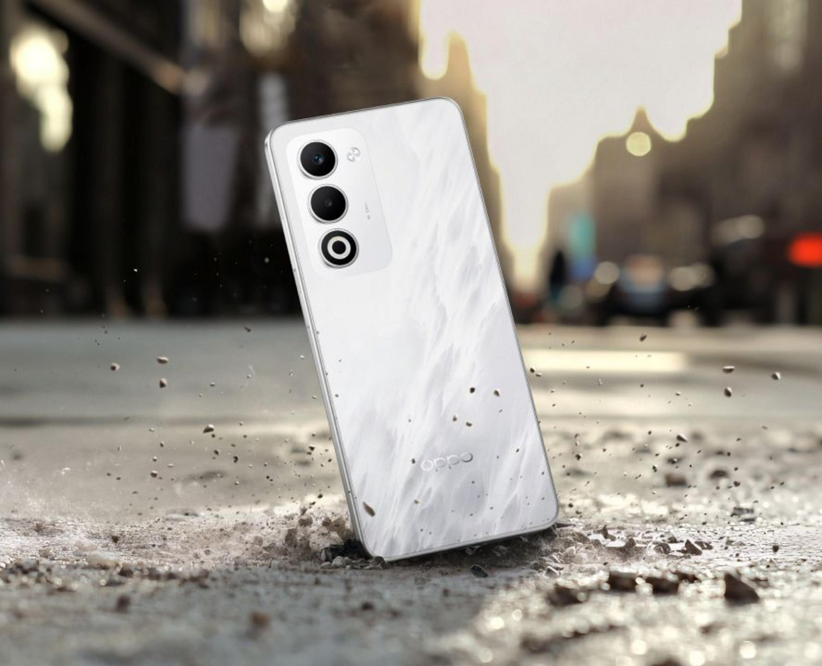 Uno smartphone Oppo bianco poggia su terreno roccioso, con polvere nell'aria.