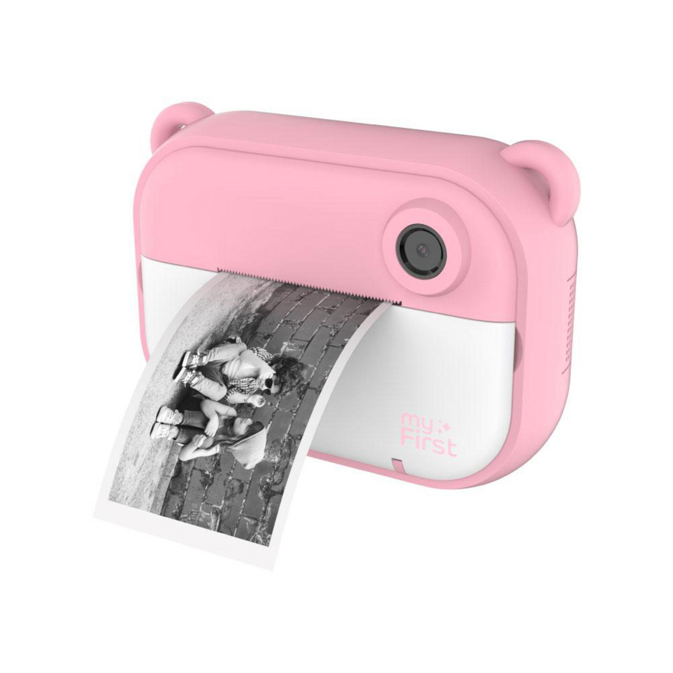 Una cámara rosa imprime una foto en blanco y negro de dos niños sobre adoquines.