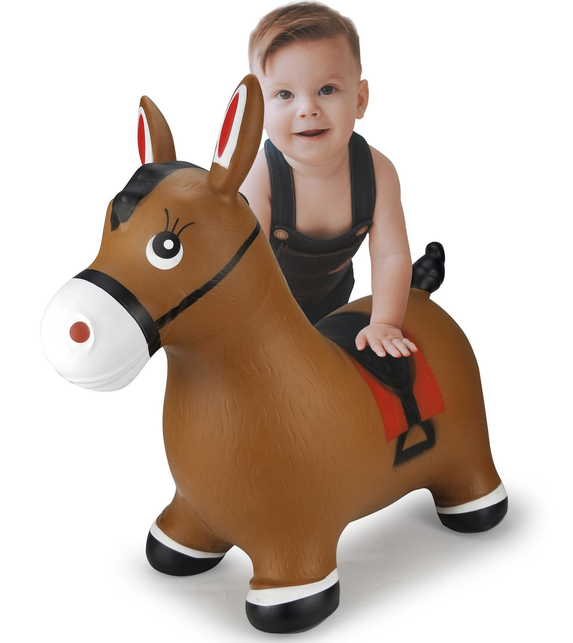 Un bambino in salopette siede su un cavallo gonfiabile marrone con orecchie rosse.