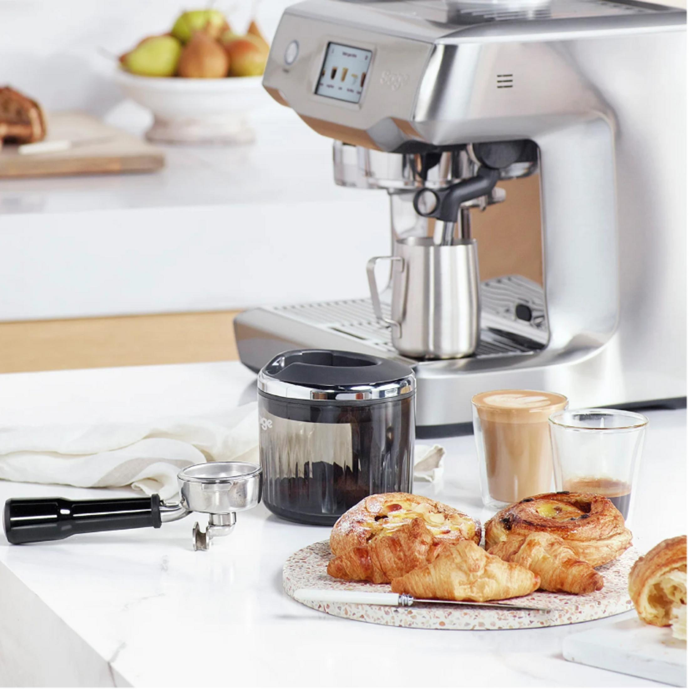 Macchina per caffè espresso con pasticcini e caffè su tavolo di marmo.
