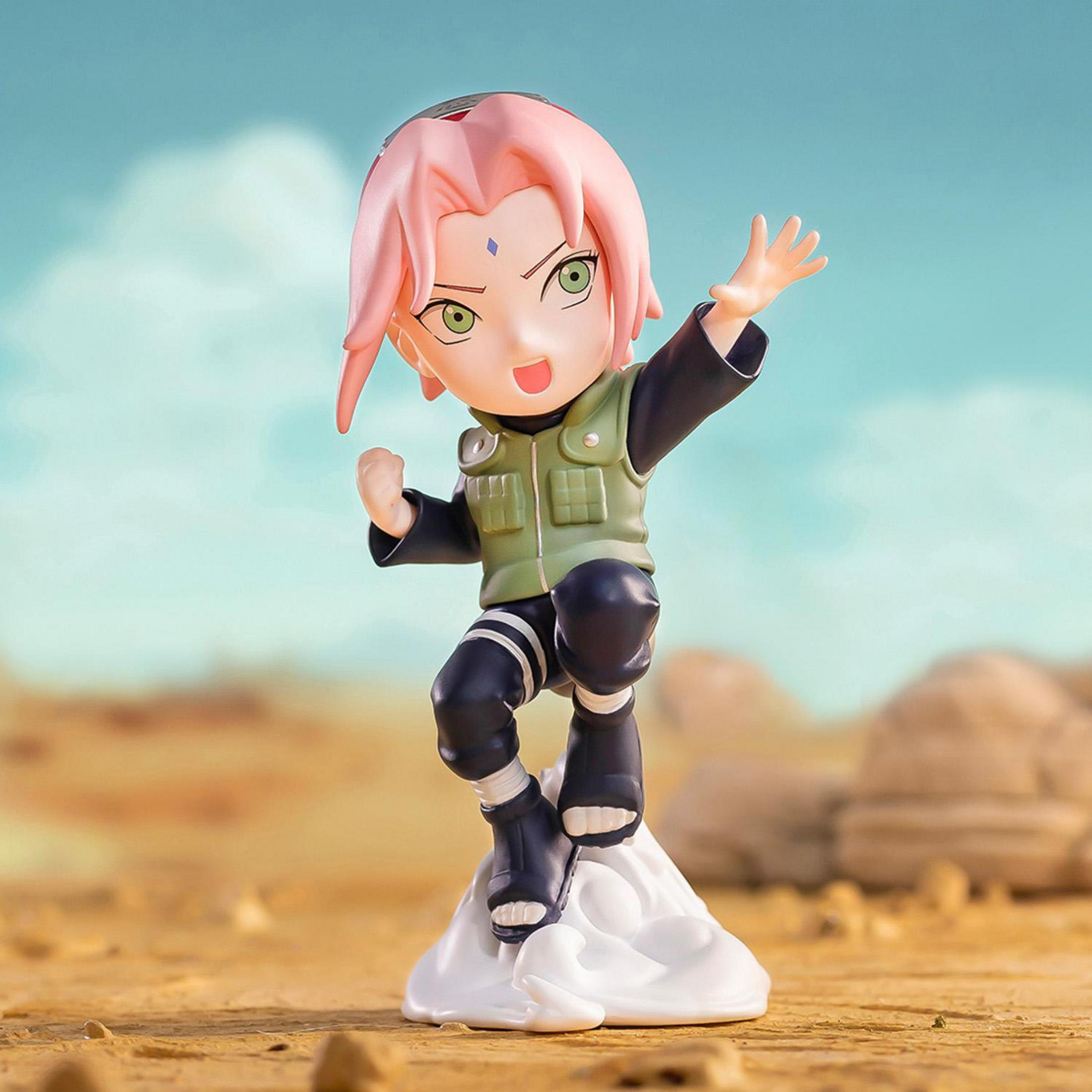 Chibi-Figur von Sakura Haruno in einer Pose auf felsigem, sandigem Boden und blauem Himmel.