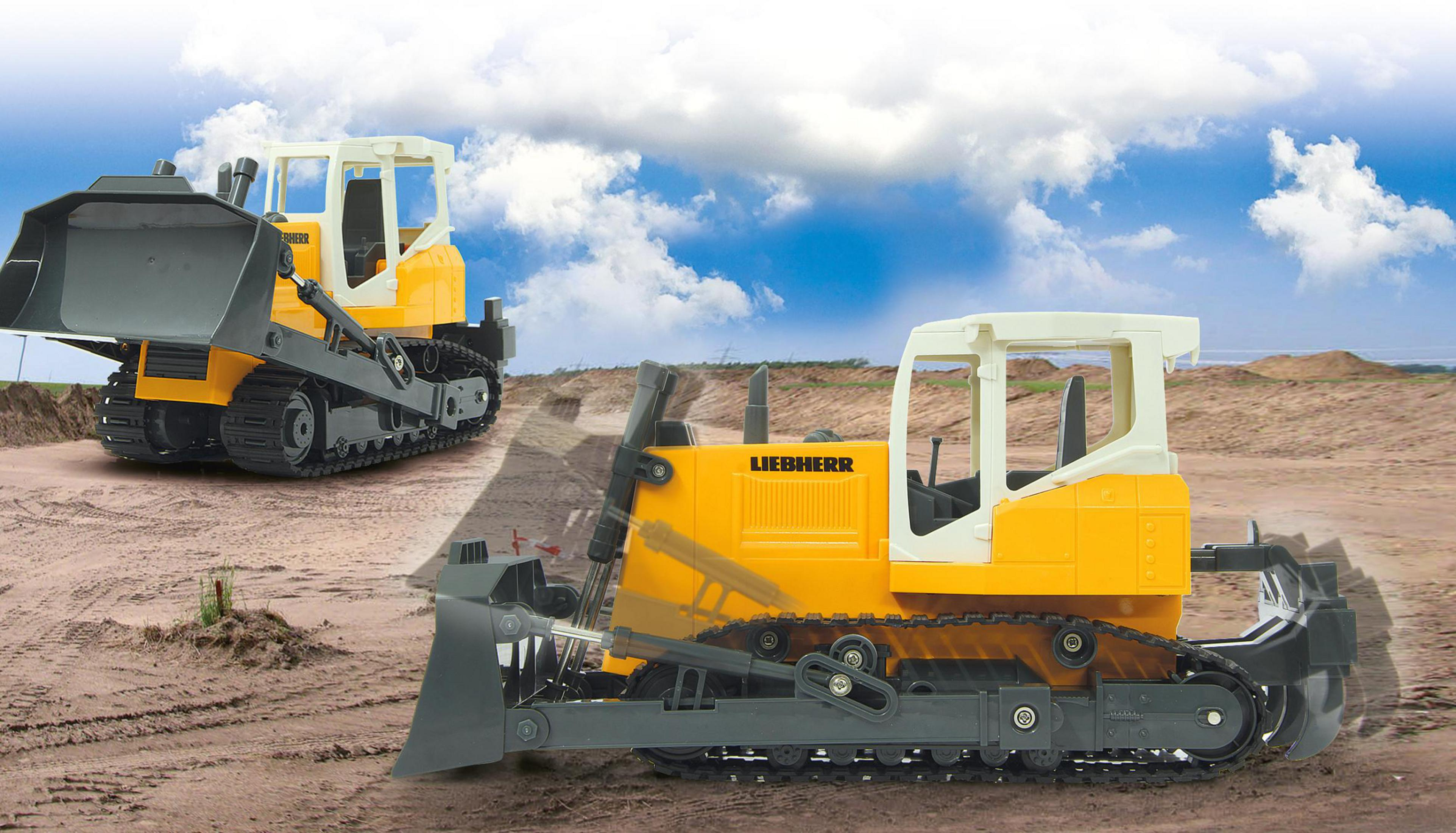 Zwei gelbe und weiße Liebherr-Planierraupen stehen auf sandigem Boden.