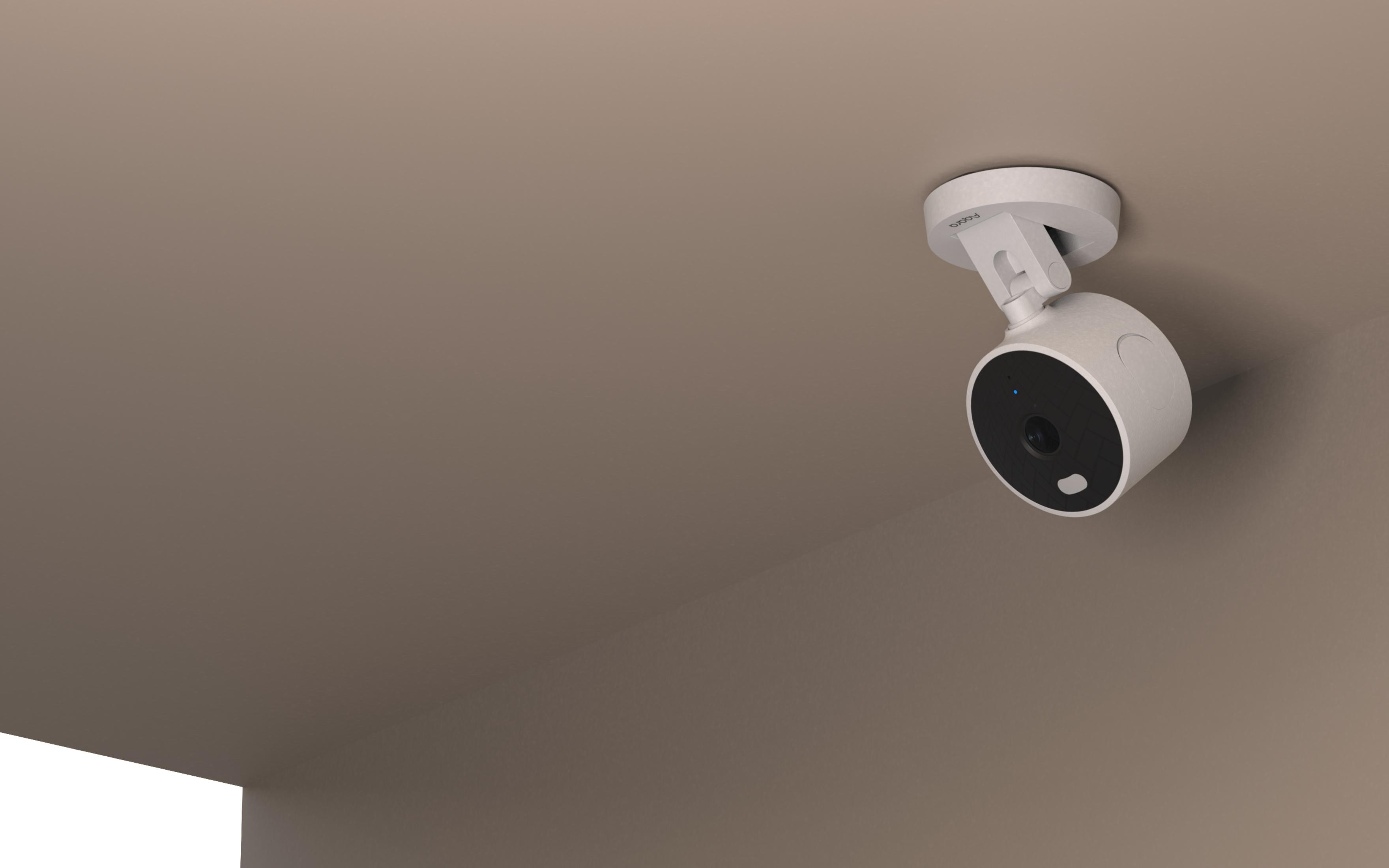 A white security camera is mounted on a ceiling. It has a black lens.