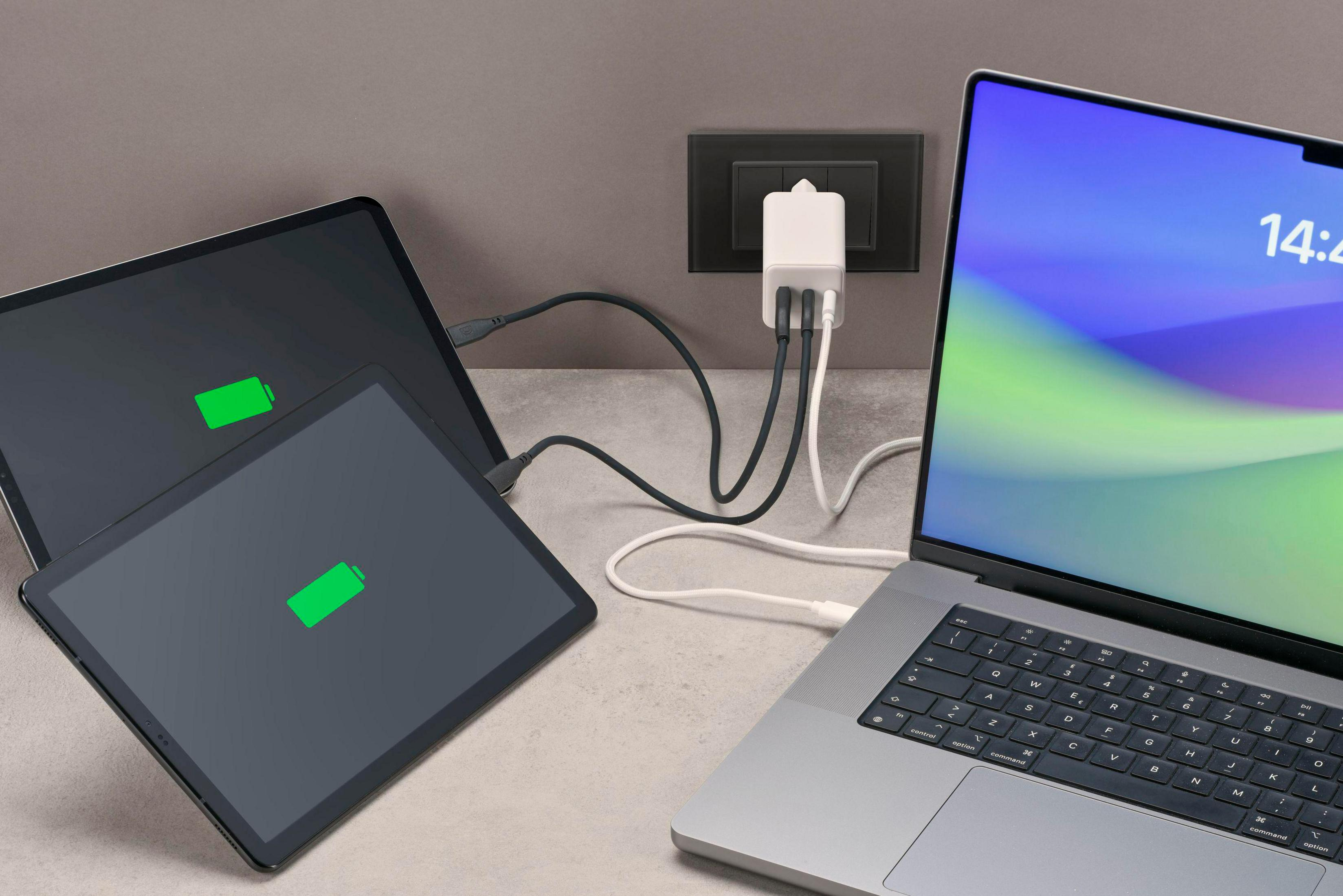 Varias tabletas y un portátil se cargan a través de un adaptador de corriente.