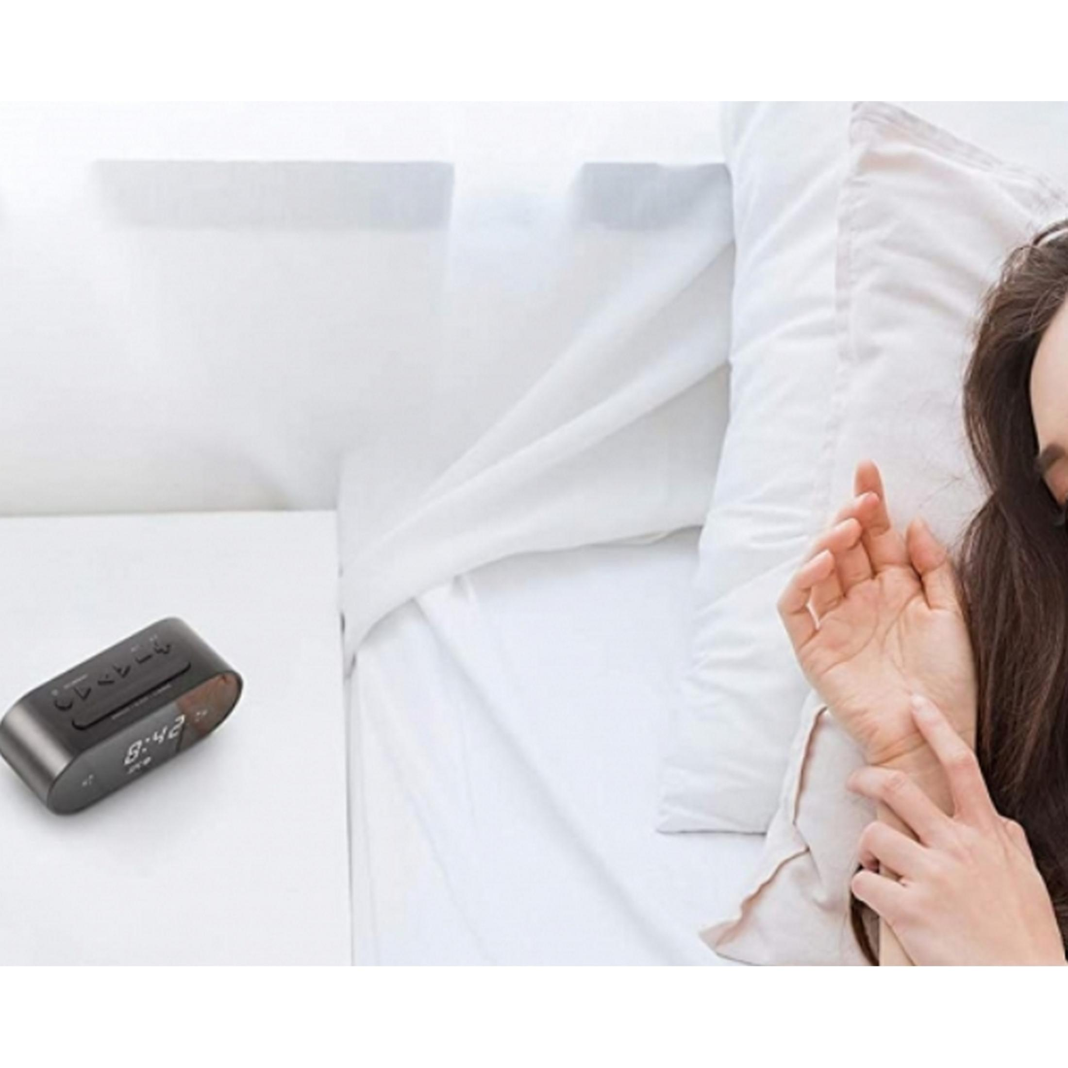 Una sveglia digitale mostra le 8:42 su un comodino accanto a una ragazza che dorme.
