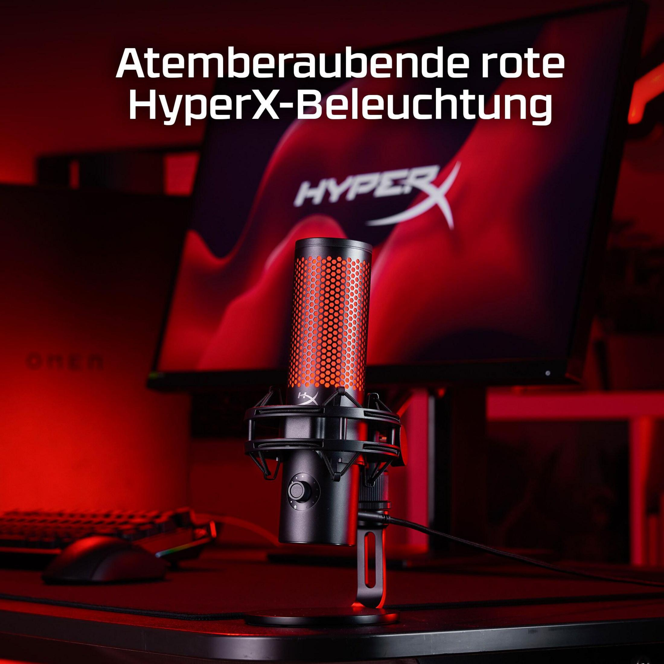 Un microphone HyperX rouge est sur un bureau, éclairé par une lumière rouge.