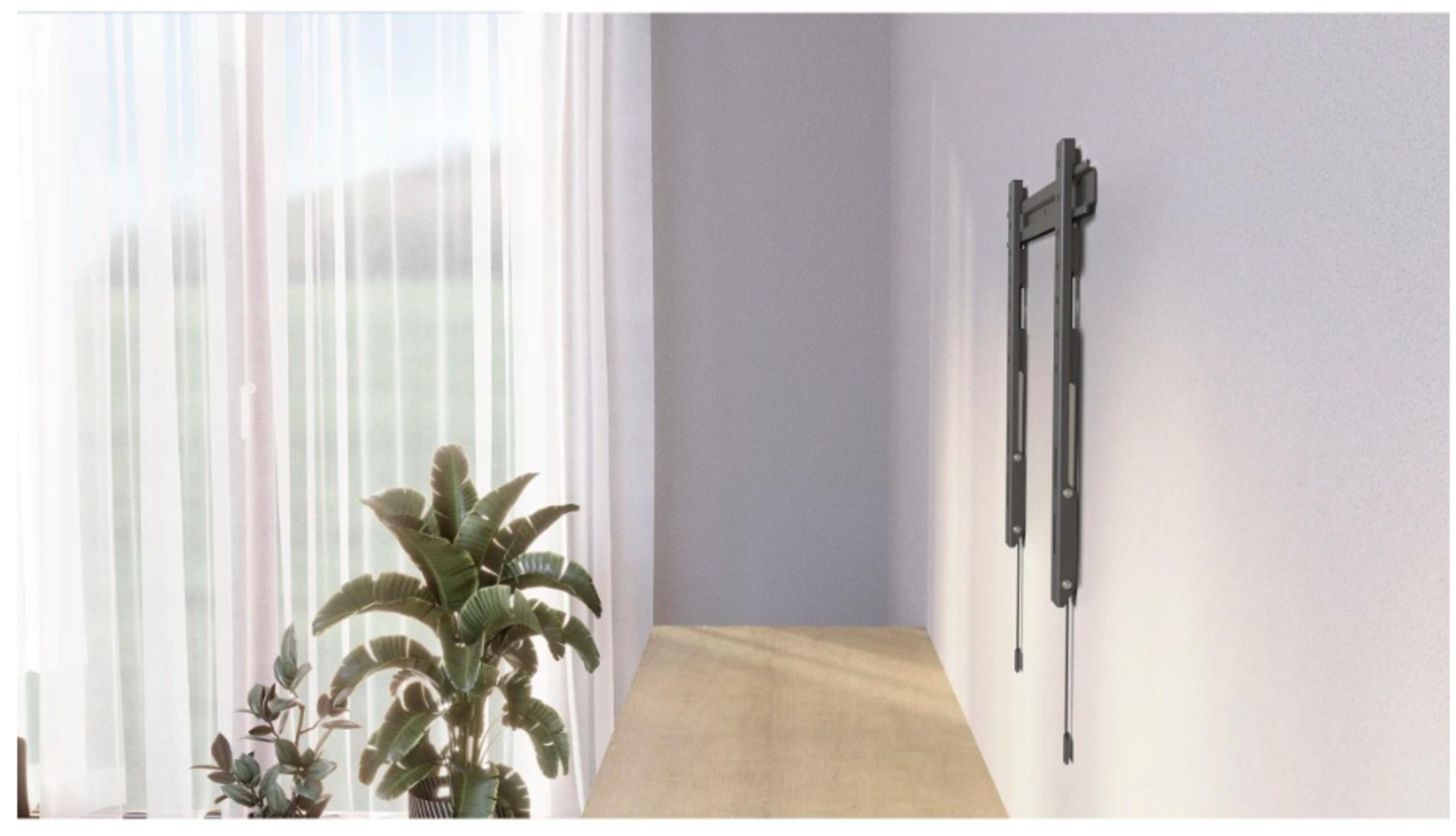 Ein dunkler TV-Wandhalter hängt an einer weißen Wand neben einem Fenster mit weißen Vorhängen.