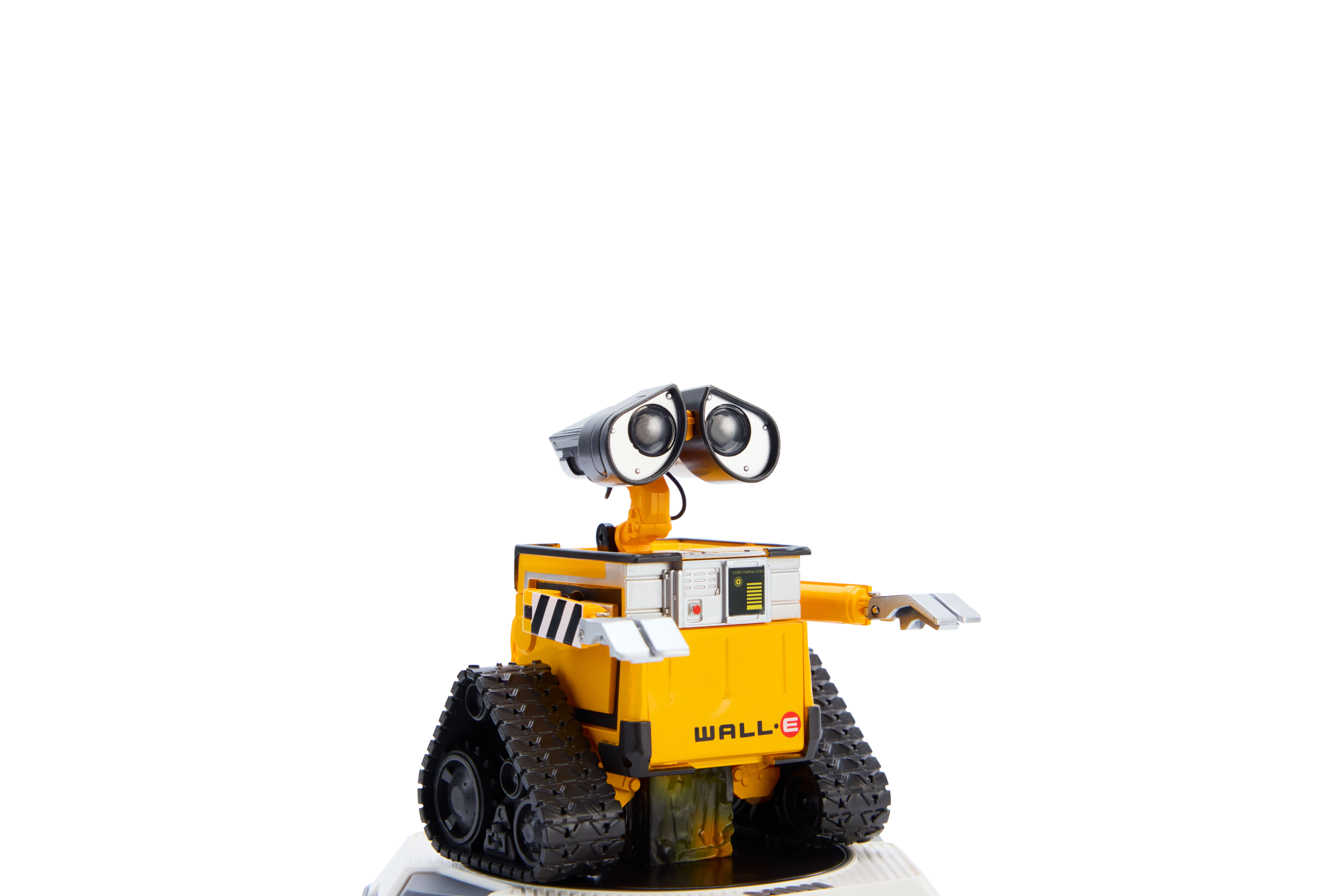 Robot amarillo con orugas y ojos grandes sobre fondo blanco.
