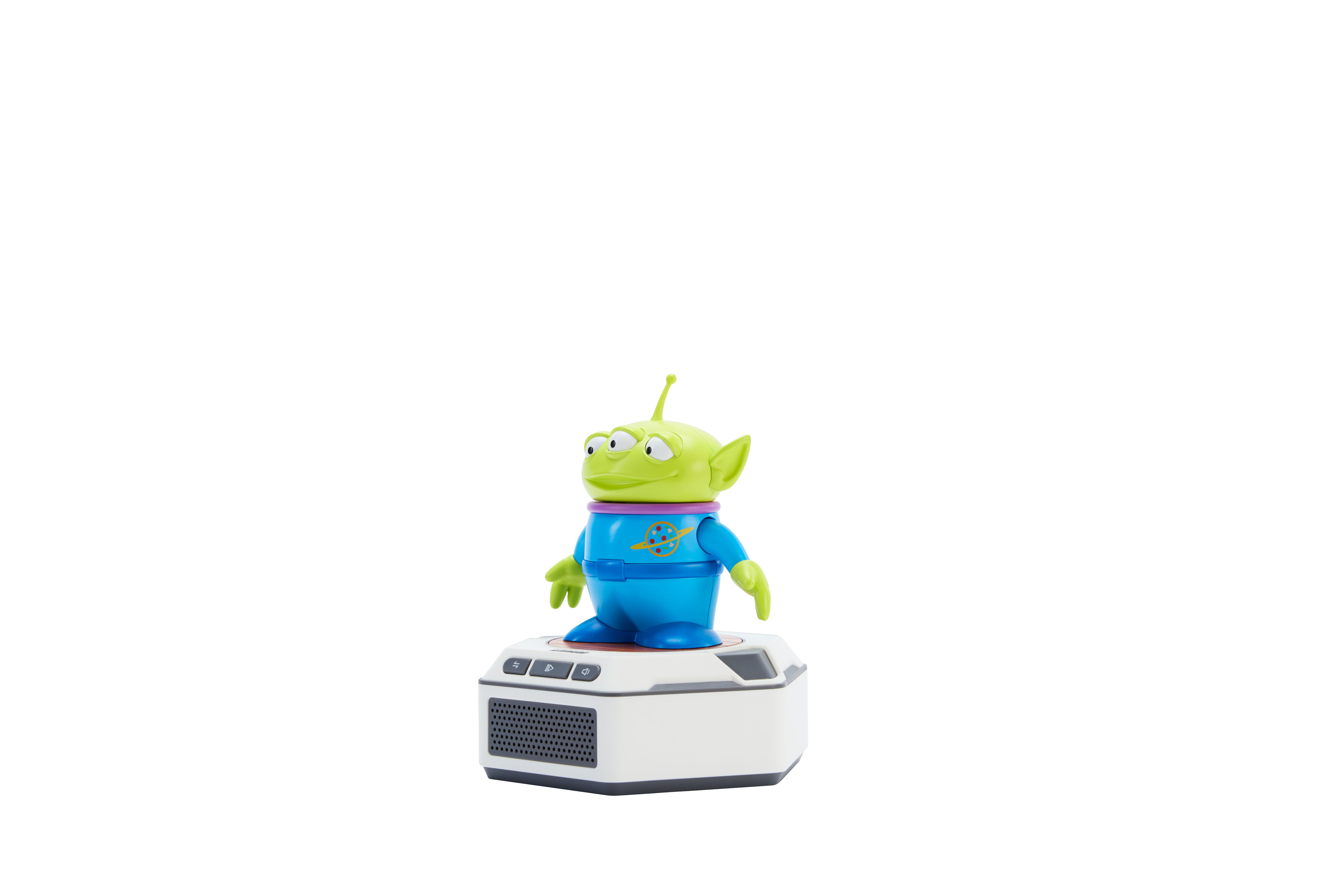 Un juguete alienígena verde con ropa azul está sobre un pedestal blanco con botones.