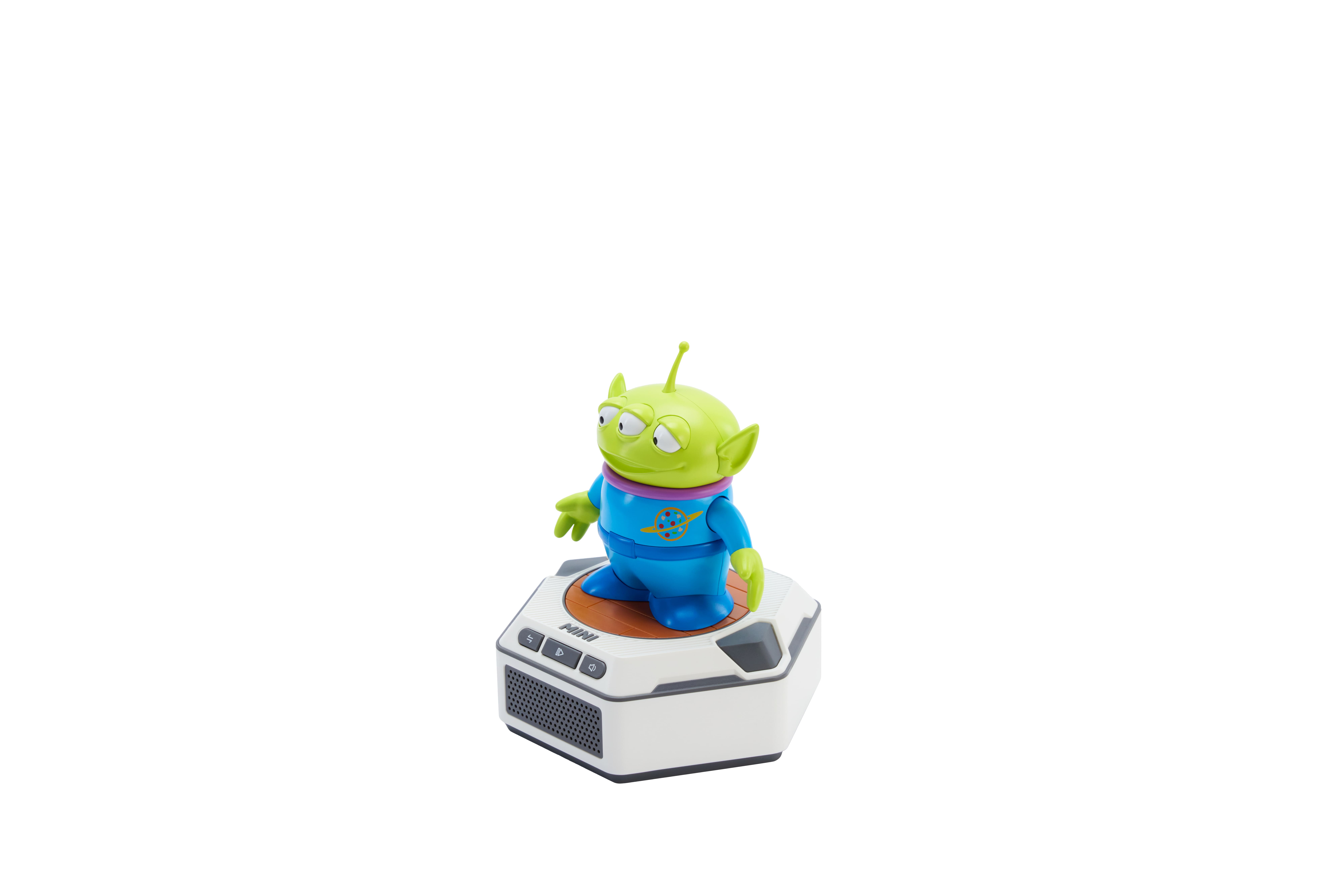 Un alienígena verde de Toy Story está sobre una plataforma blanca con altavoces.
