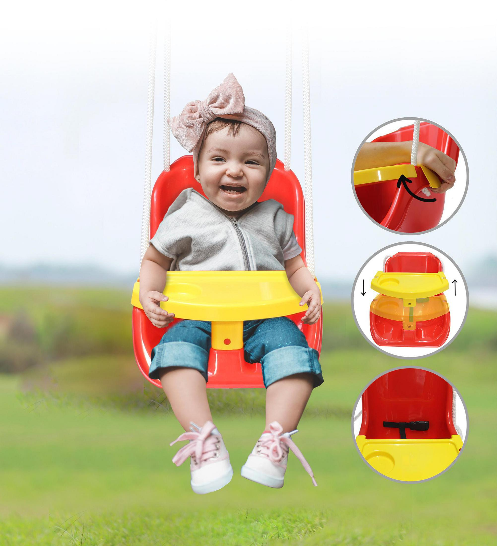 Ein Baby in einem roten Schaukelsitz mit gelber Ablage, im Freien auf einer grünen Wiese.