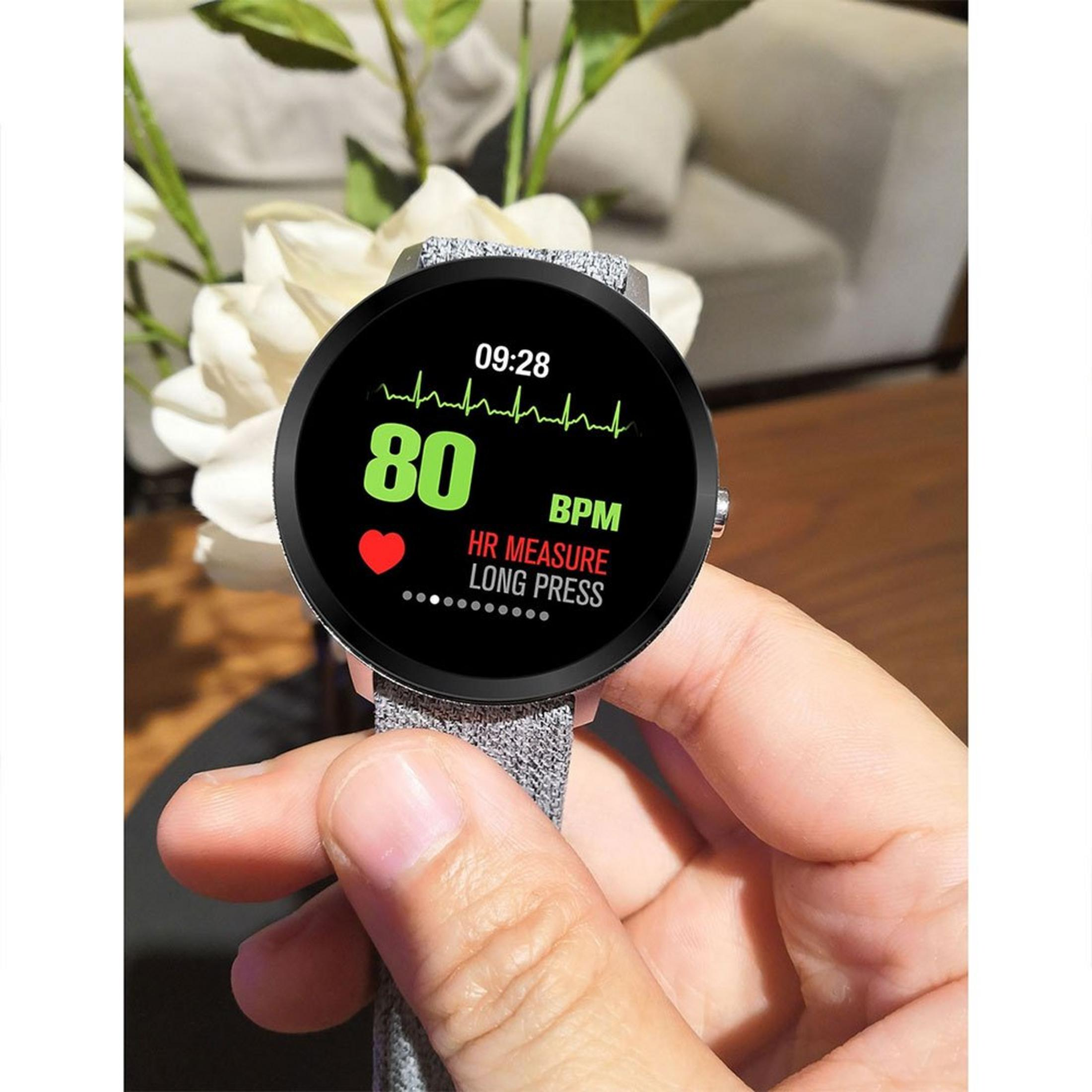Uno smartwatch mostra 80 BPM di frequenza cardiaca. Una mano tiene l'orologio con sfondo sfocato.