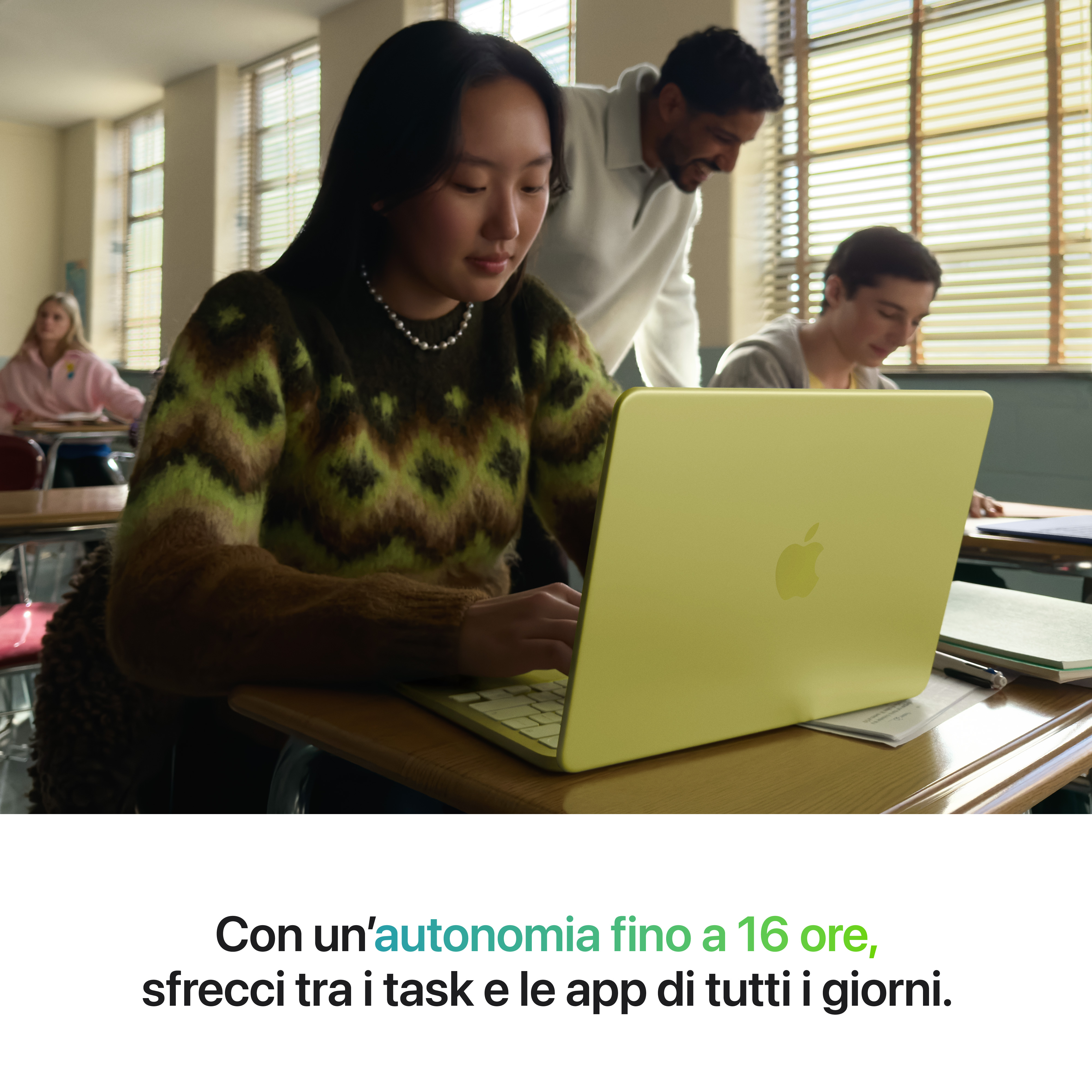 Studenti in aula usano laptop, un insegnante è alle loro spalle.