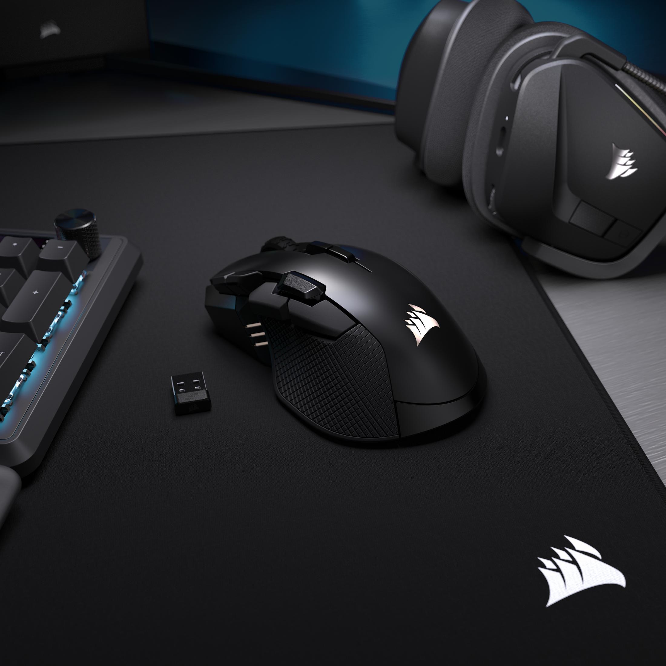 Mouse, tastiera, dongle e cuffie da gaming neri su un tappetino nero.
