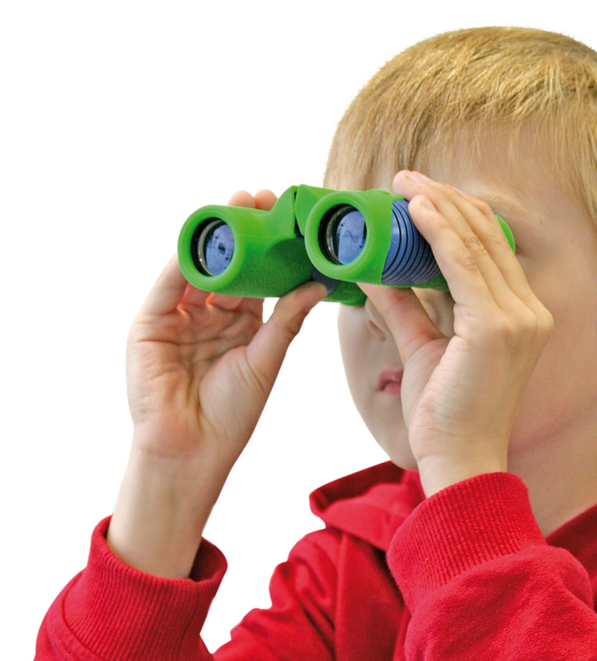 Un bambino biondo con una maglietta rossa tiene un binocolo verde sugli occhi, guardando attentamente in avanti su uno sfondo bianco.