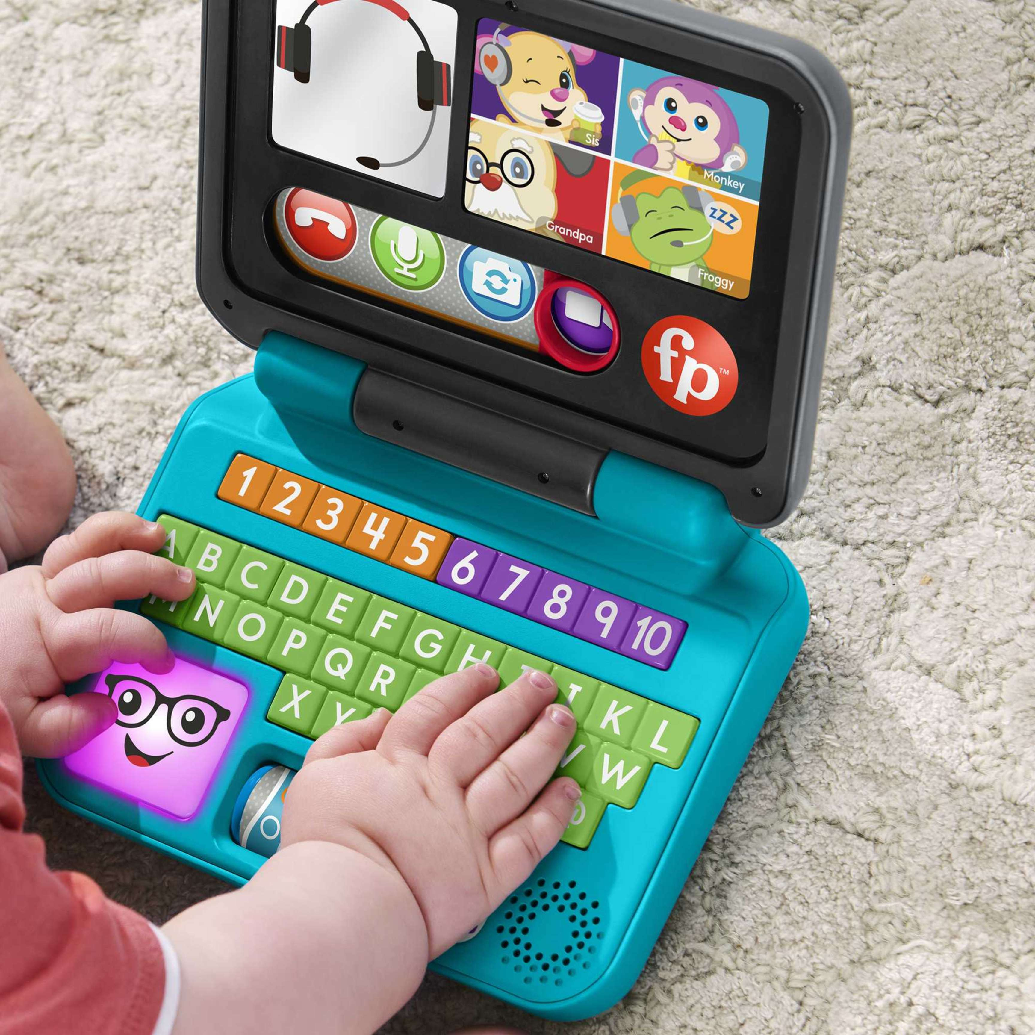Ein Baby spielt mit einem blauen Laptop-Spielzeug mit Buchstaben und Zahlen.