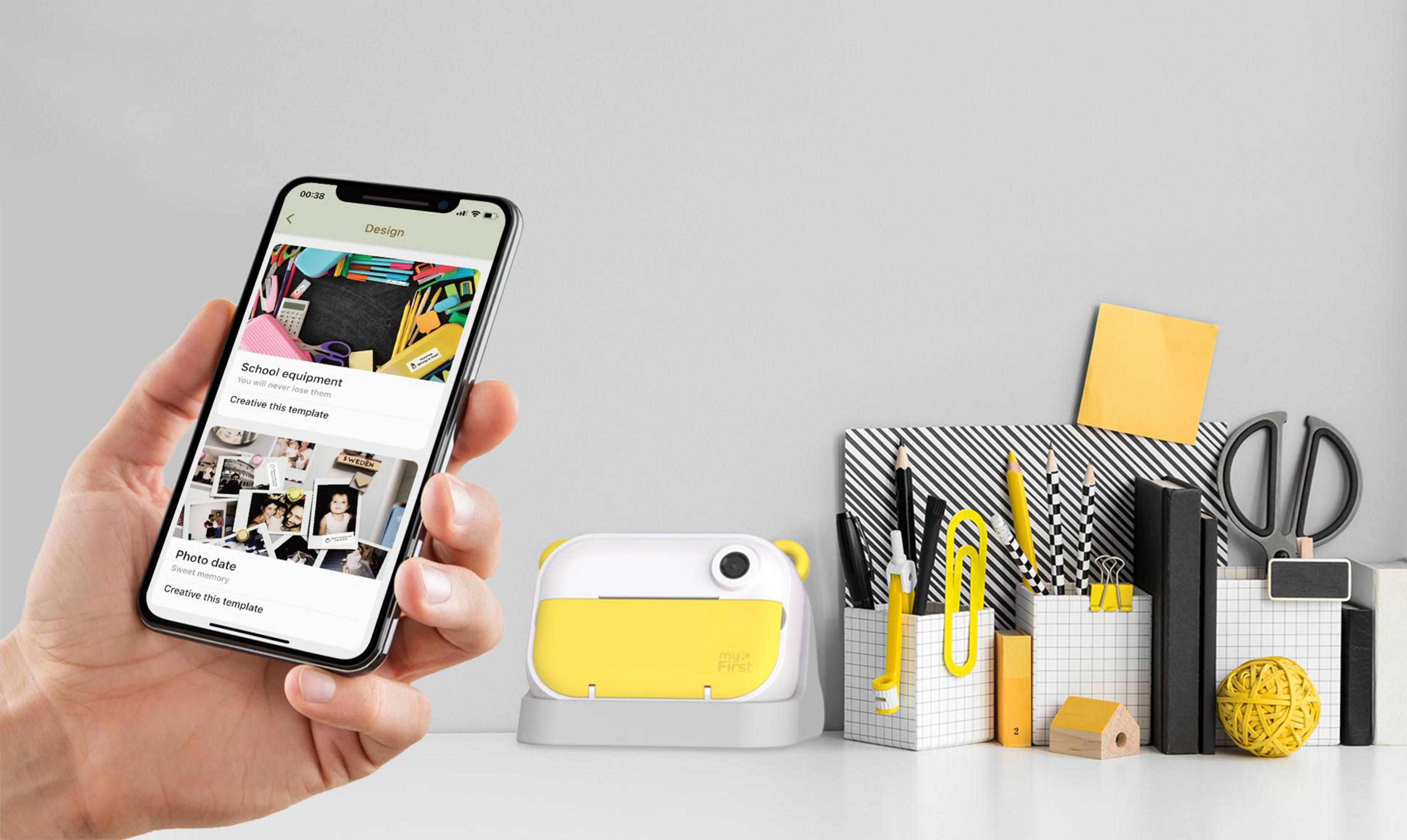 Hand hält Smartphone vor Mini-Drucker & Büromaterial. Gelber Aufkleber.