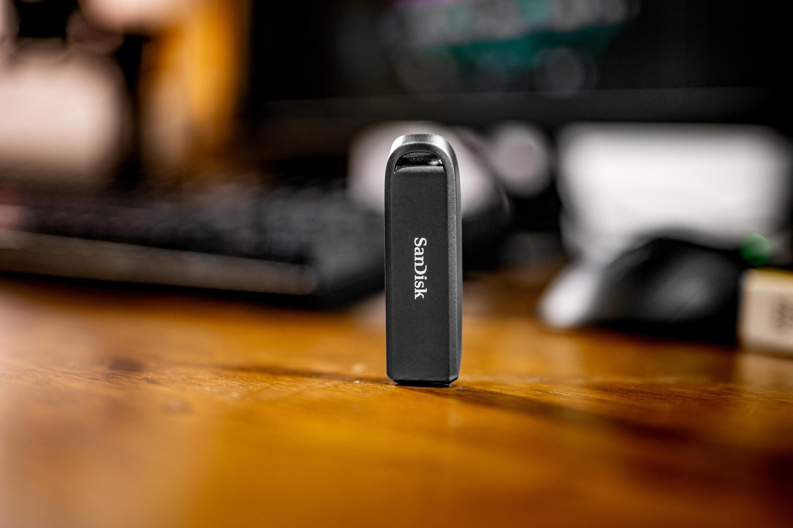 Un'unità USB SanDisk nera su un tavolo di legno. Sfondo sfocato.