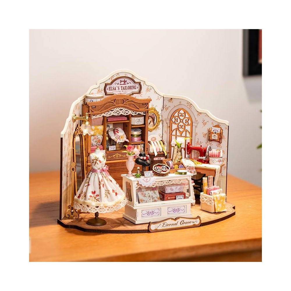 Miniatur-Schneiderladen mit Schaufensterpuppe, Nähmaschine und Stoffrollen.