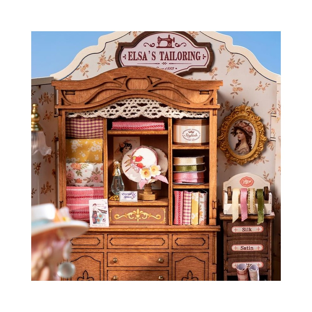 Eine Miniatur-Schneiderei mit Holzschrank, Stoffen, Bändern und Hut.