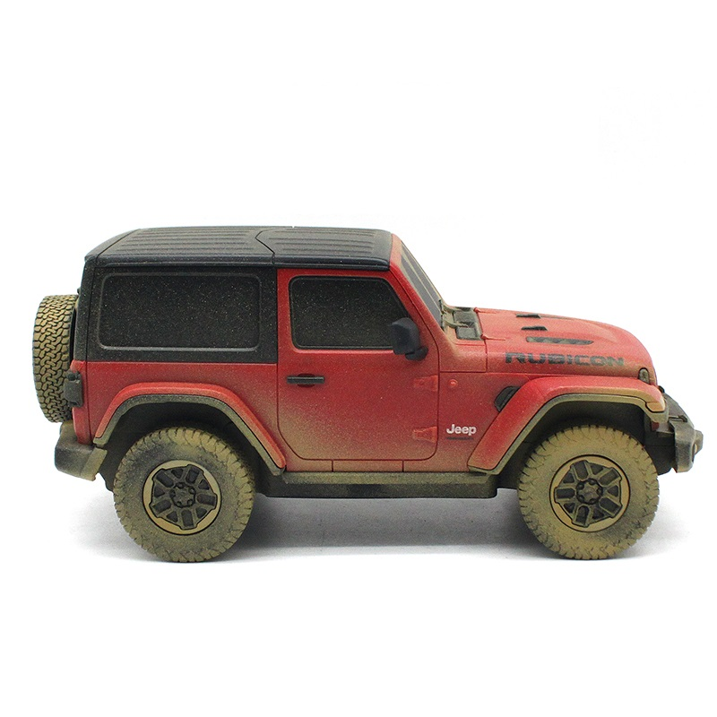 Czerwony samochód zabawka Jeep Rubicon, zakurzony, z czarnym dachem i kołem zapasowym.