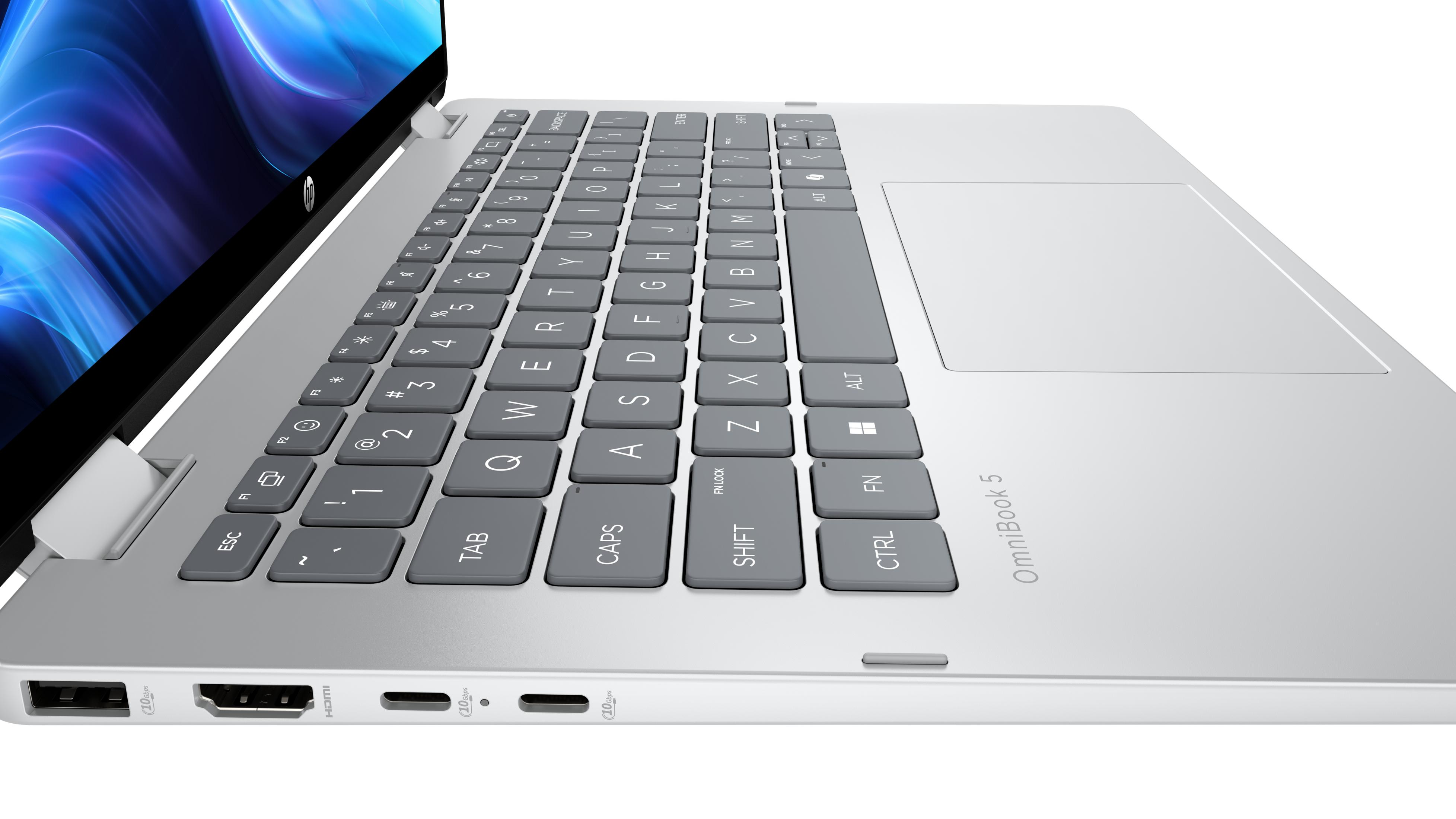 Silberner Laptop mit Tastatur, Touchpad und Anschlüssen. Heller Hintergrund.