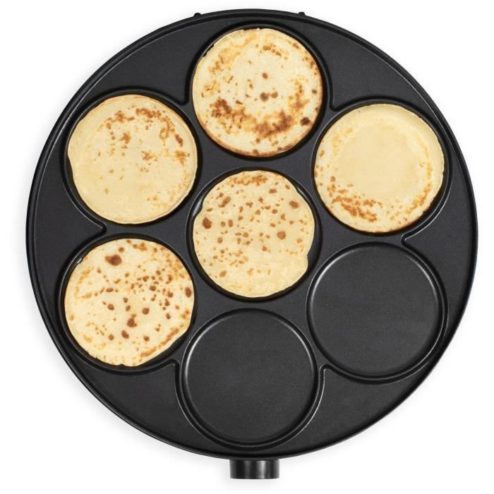 Ein schwarzer elektrischer Crêpe-Maker mit fünf goldbraunen Crêpes, die in runden Formen garen.