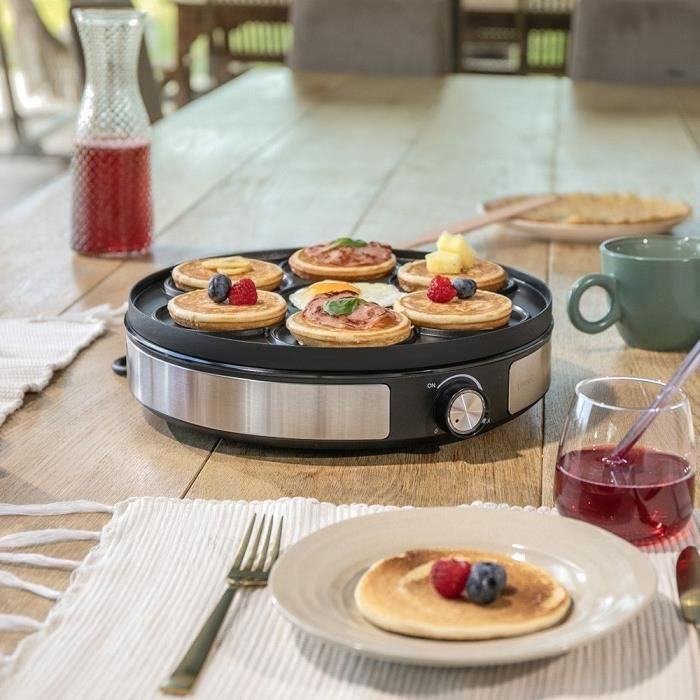 Ein runder Pfannkuchengrill mit mehreren Pfannkuchen, Beeren und einem Spiegelei.