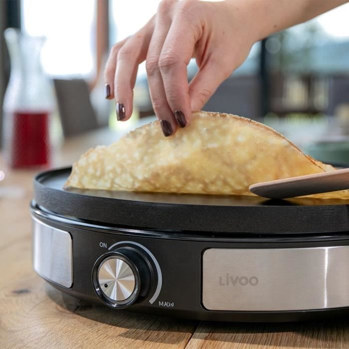 Eine Hand dreht einen Crêpe auf einer Livoo-Platte.