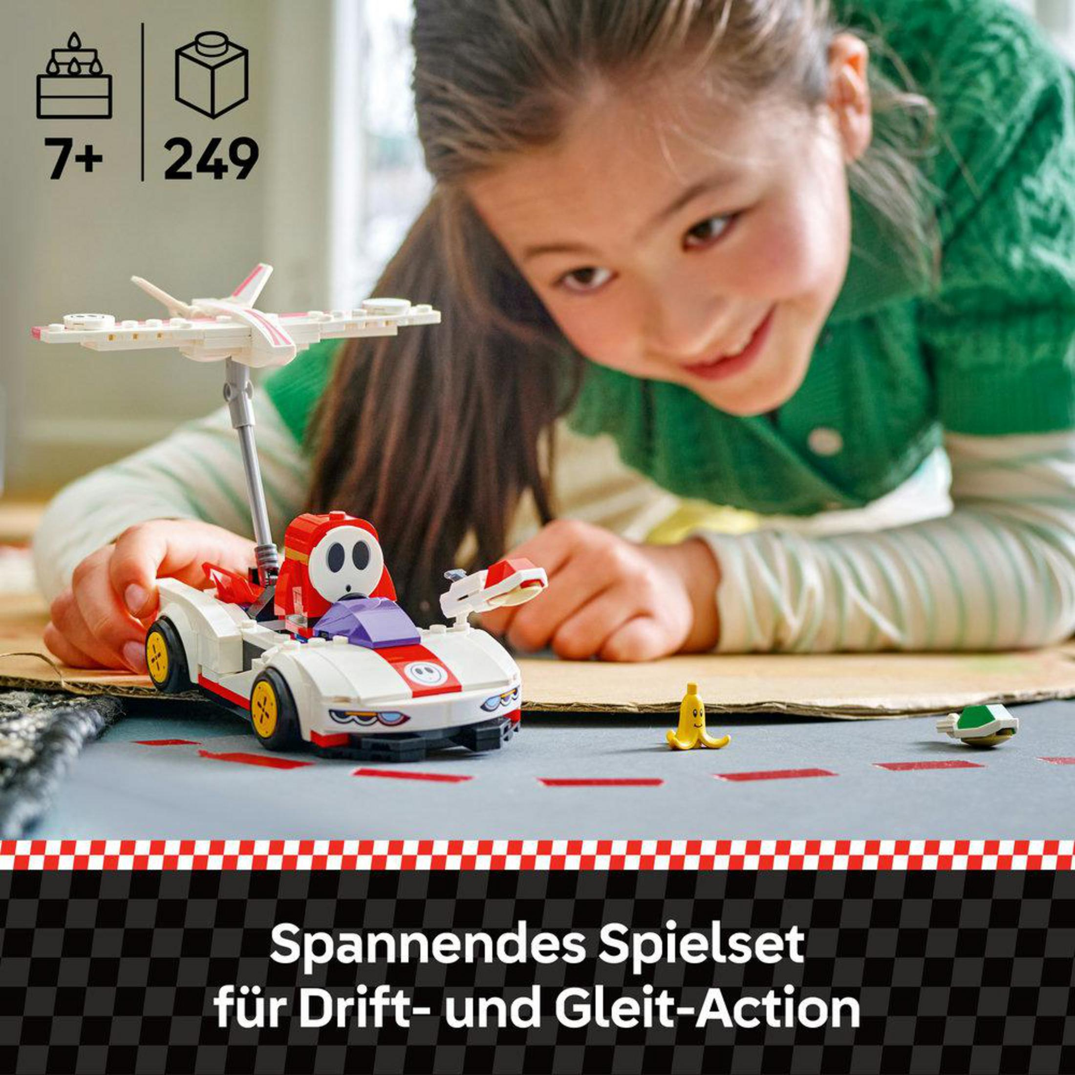 Ein Mädchen baut ein Lego-Auto mit Shy Guy und Flugzeugteilen.