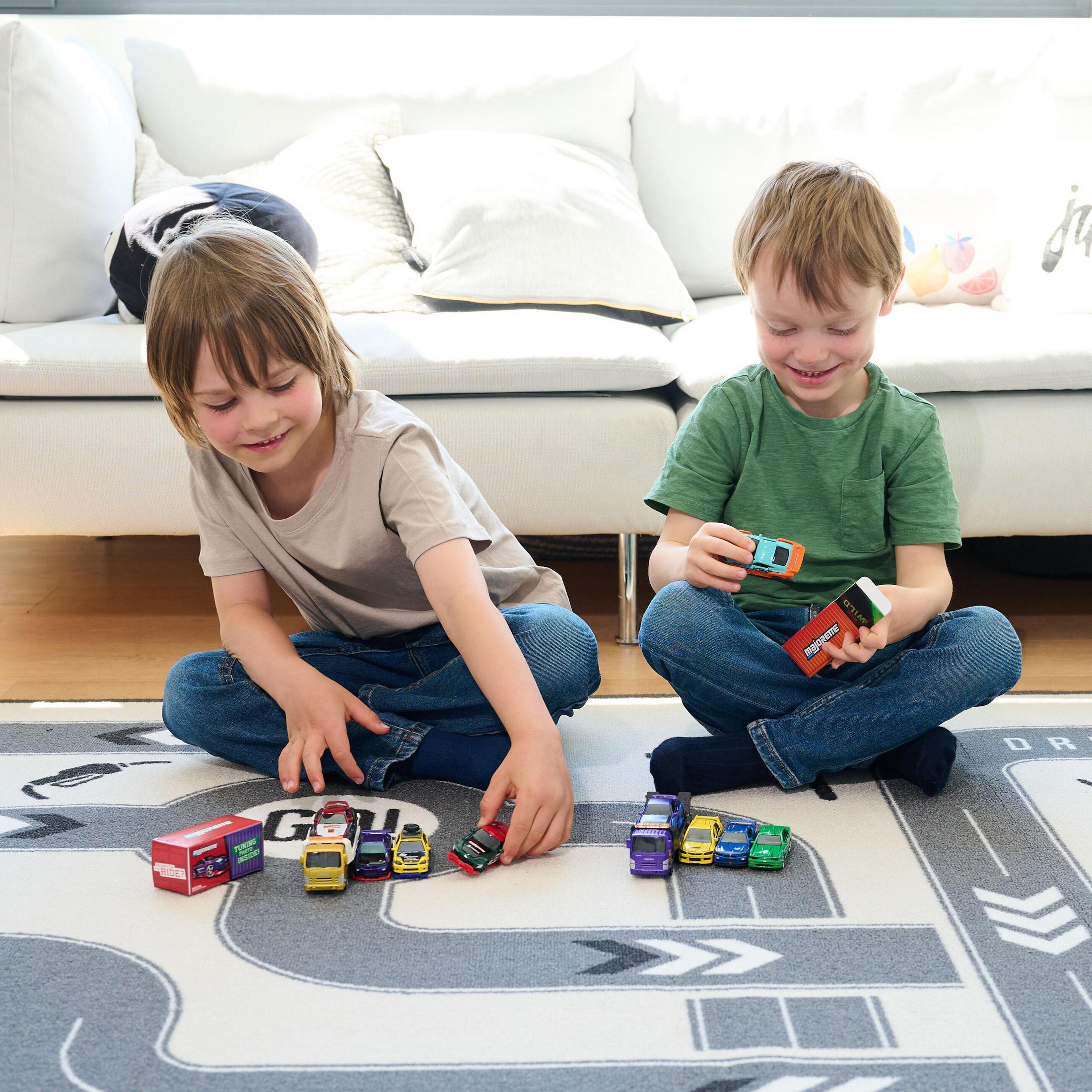Zwei Jungen spielen mit Spielzeugautos auf einer Teppichbahn.