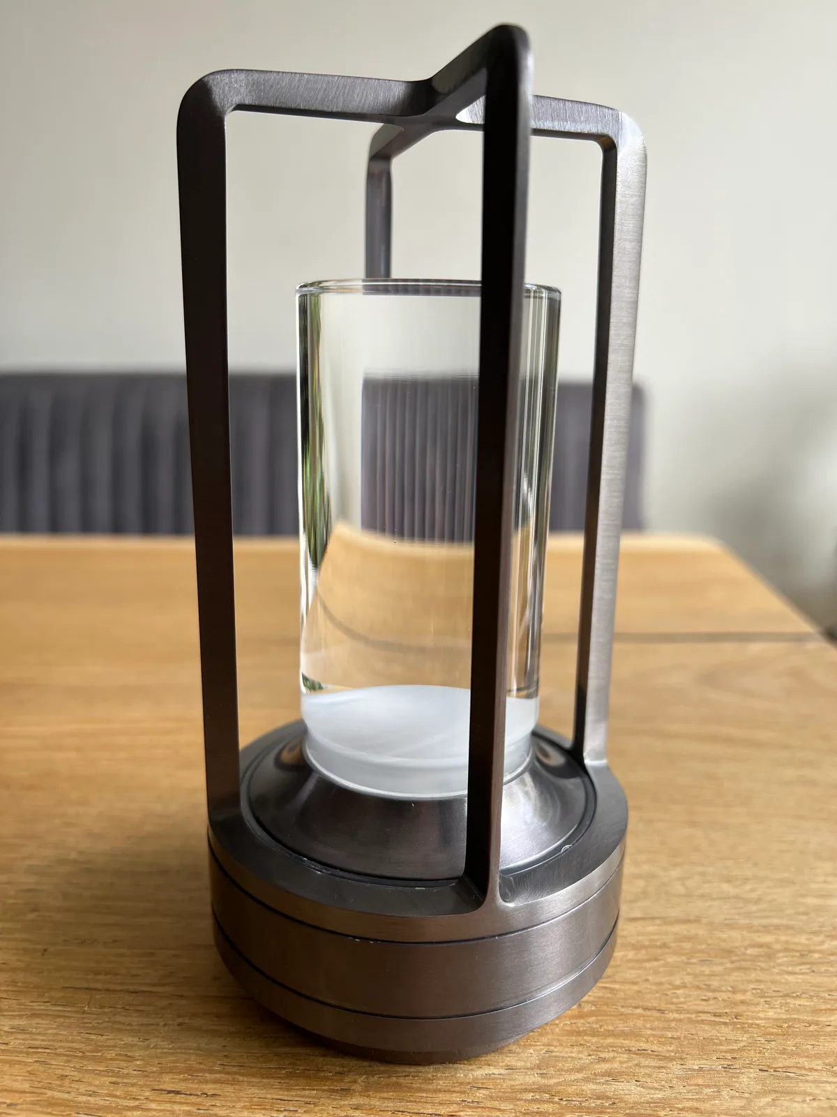 Ein moderner Metallkerzenständer mit Glaszylinder und weißer Basis.