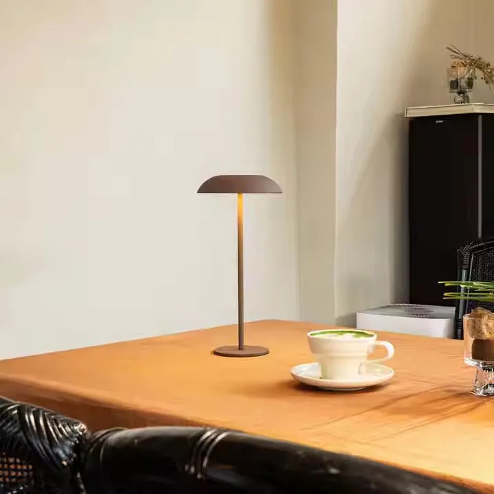 Eine braune Tischlampe leuchtet auf einem orangefarbenen Tisch neben einer weißen Tasse.
