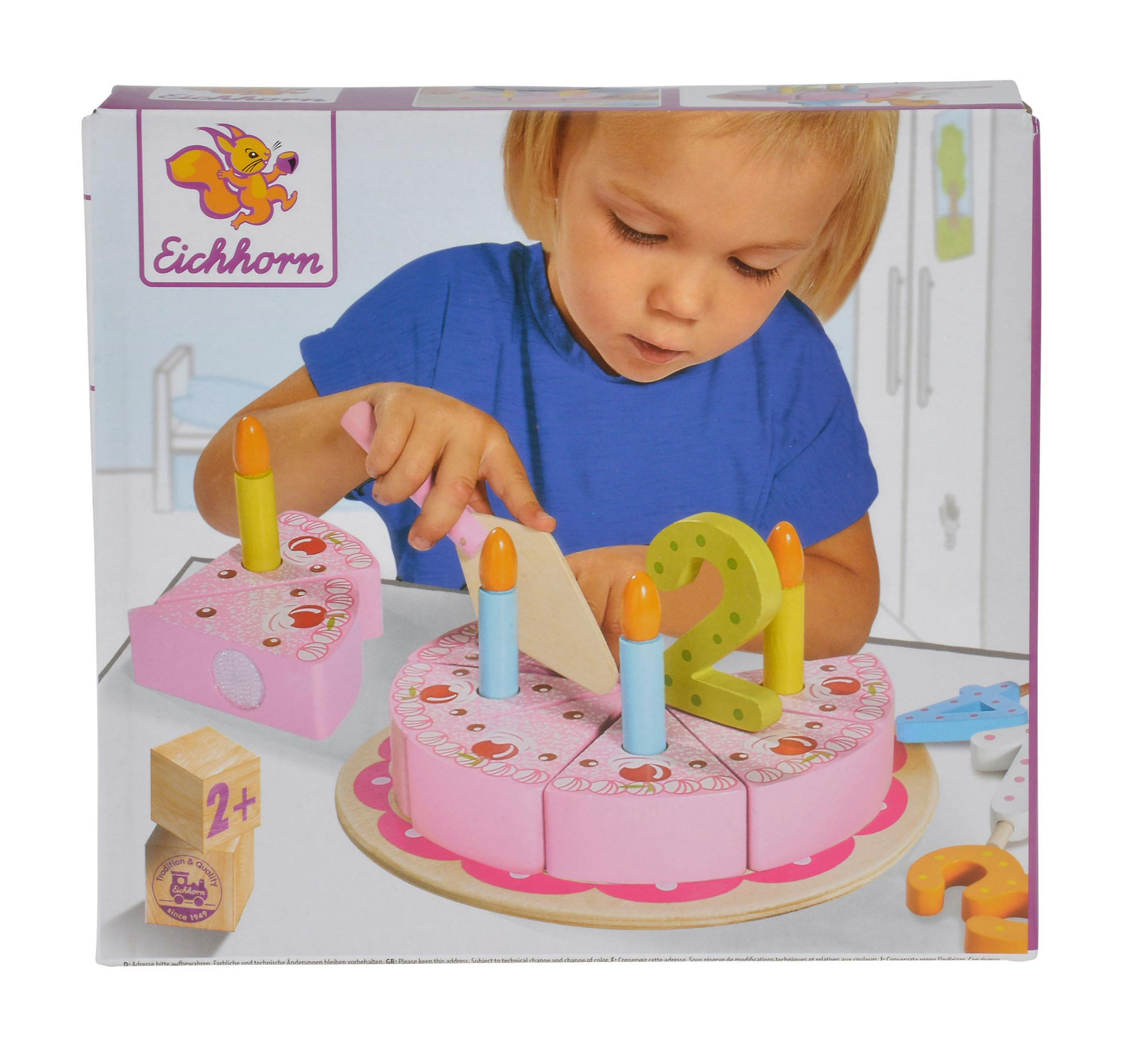 Ein Kind schneidet einen hölzernen rosa Kuchen mit Kerzen und der Zahl 2.