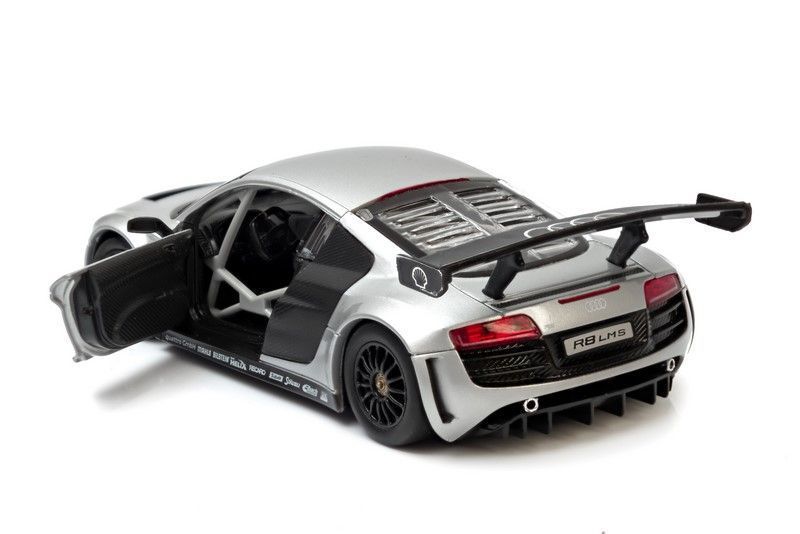 Srebrny samochód wyścigowy Audi R8 LMS z otwartymi drzwiami, klatką i dużym skrzydłem.