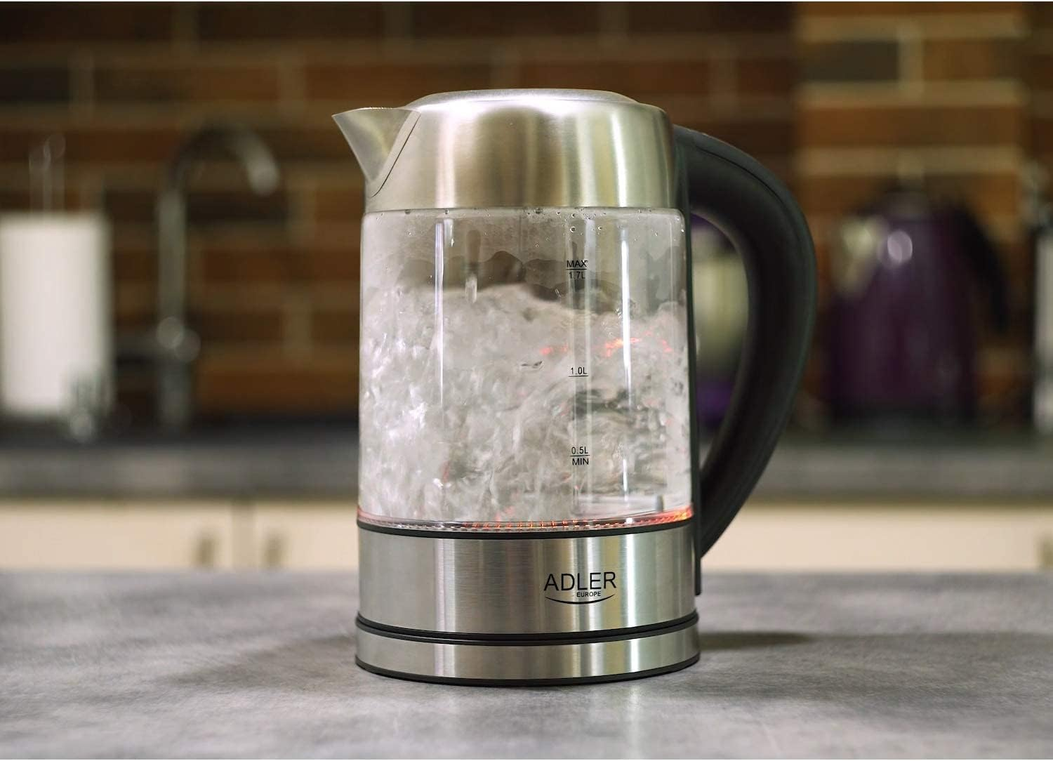 Ein elektrischer Wasserkocher aus Glas mit kochendem Wasser auf einer Küchentheke.