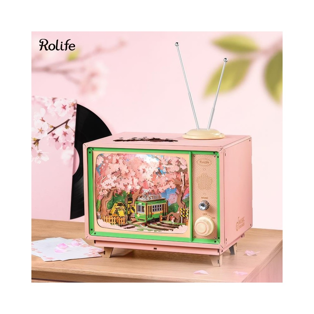 Kiraz çiçekleri altında minyatür bir sahneye sahip pembe retro TV.