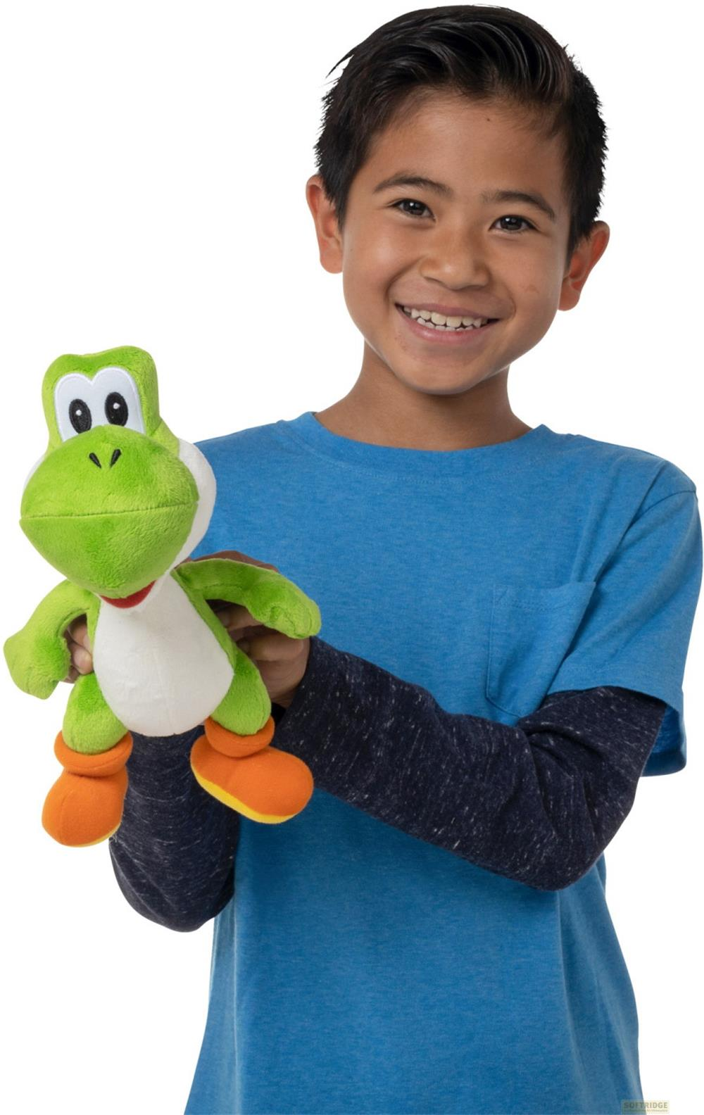 Un niño con camisa azul sostiene un peluche verde de Yoshi.