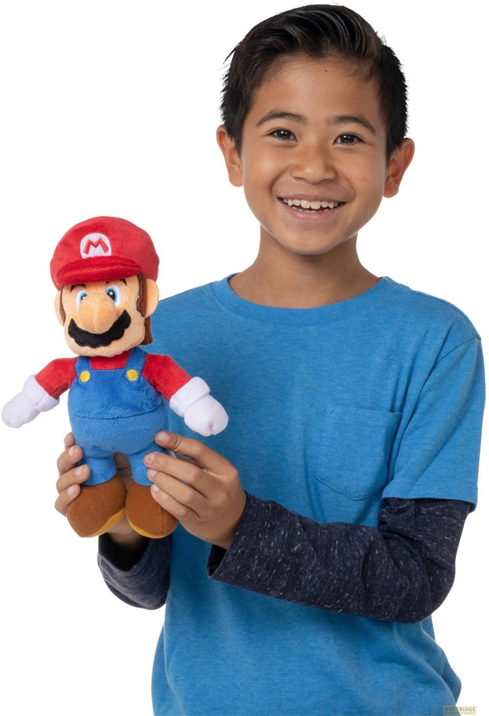 Un niño sonriente con camisa azul sostiene un peluche de Mario. Fondo blanco.