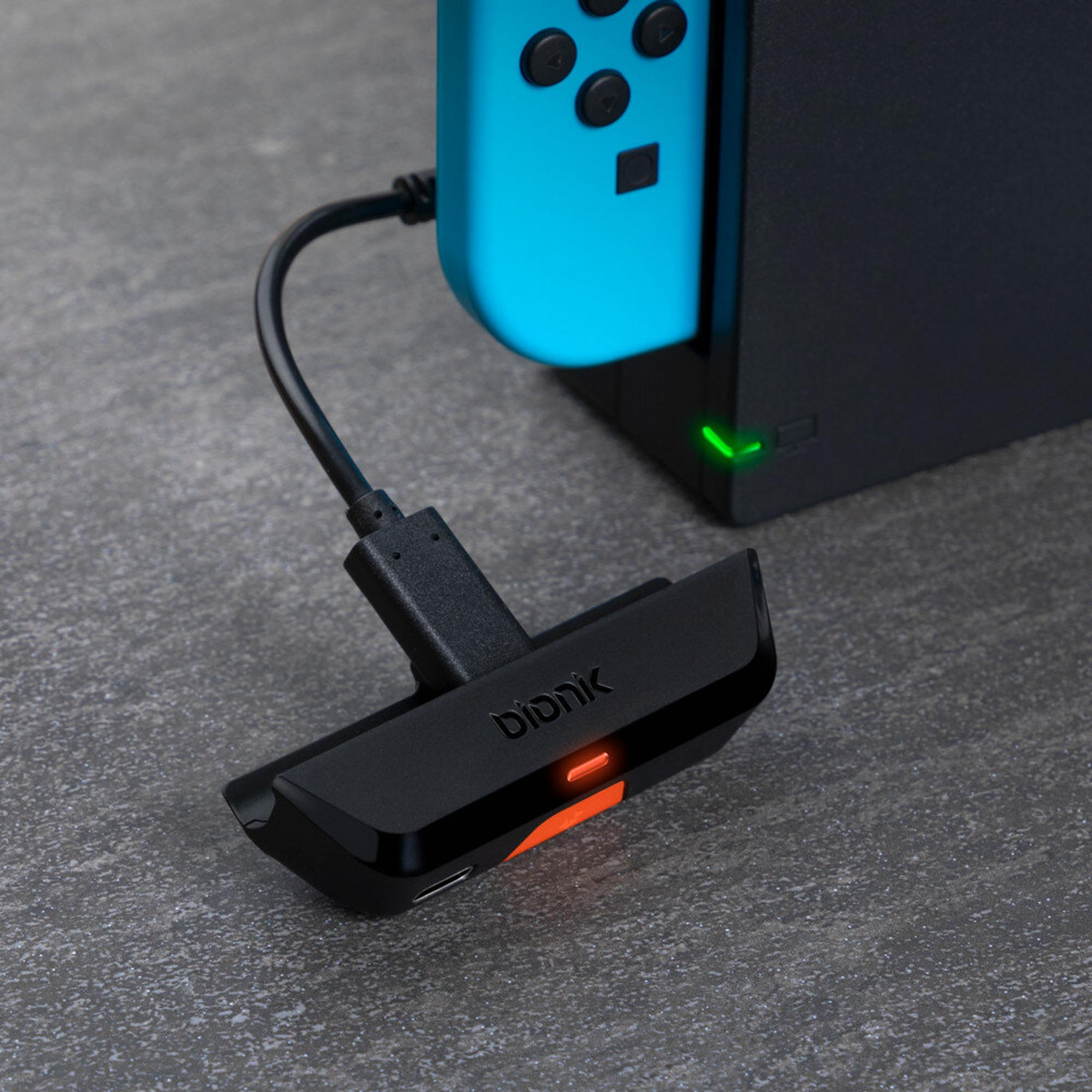 Niebieski kontroler Nintendo Switch jest podłączony do czarnej stacji dokującej.