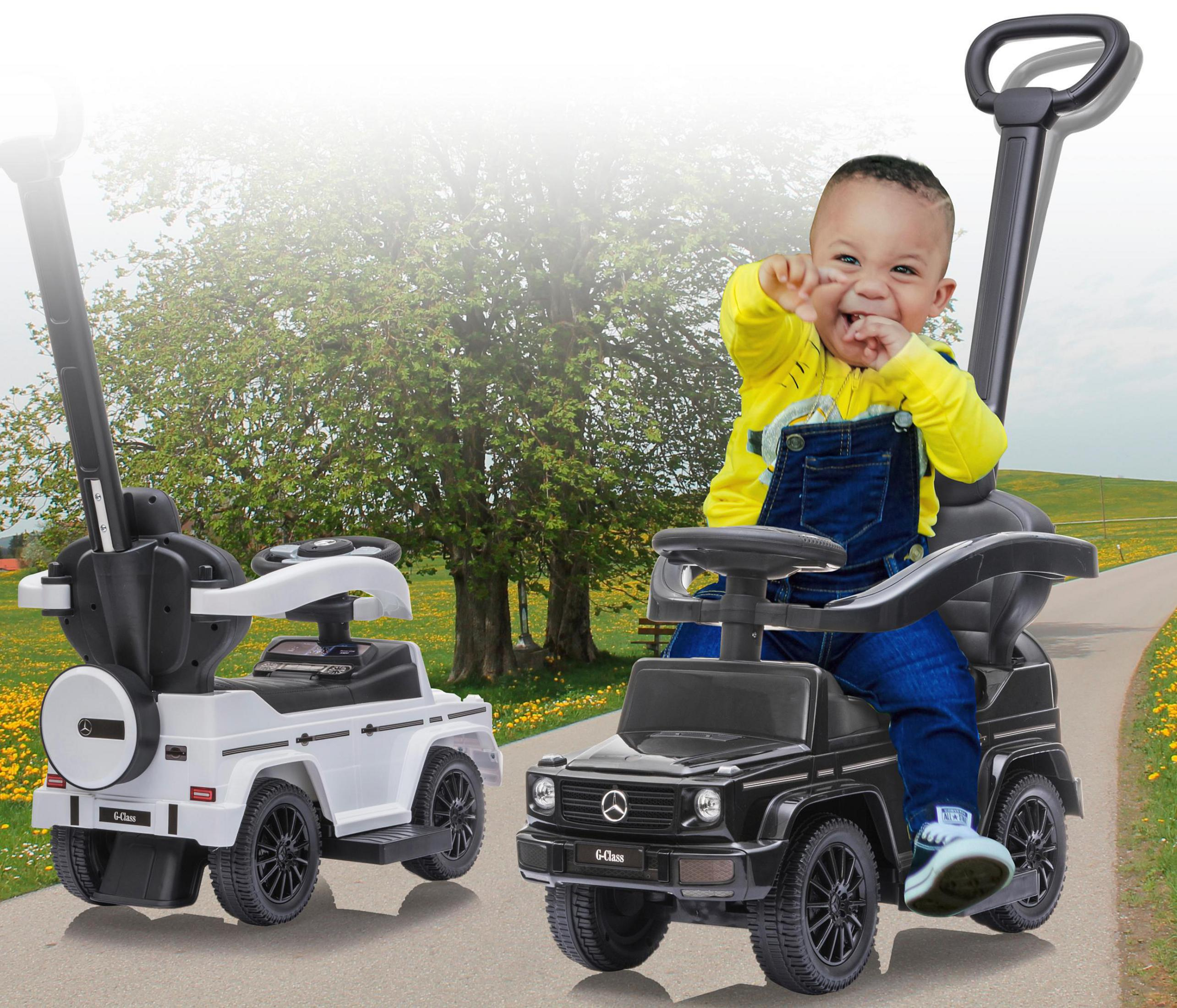 Ein Baby sitzt in einem schwarzen Spielzeugauto. Ein weißes Spielzeugauto steht daneben.