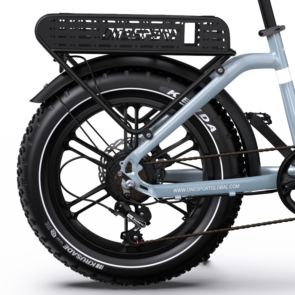 Nahaufnahme des Hinterrads eines hellgrauen E-Bikes mit Gepäckträger und Kenda-Reifen.