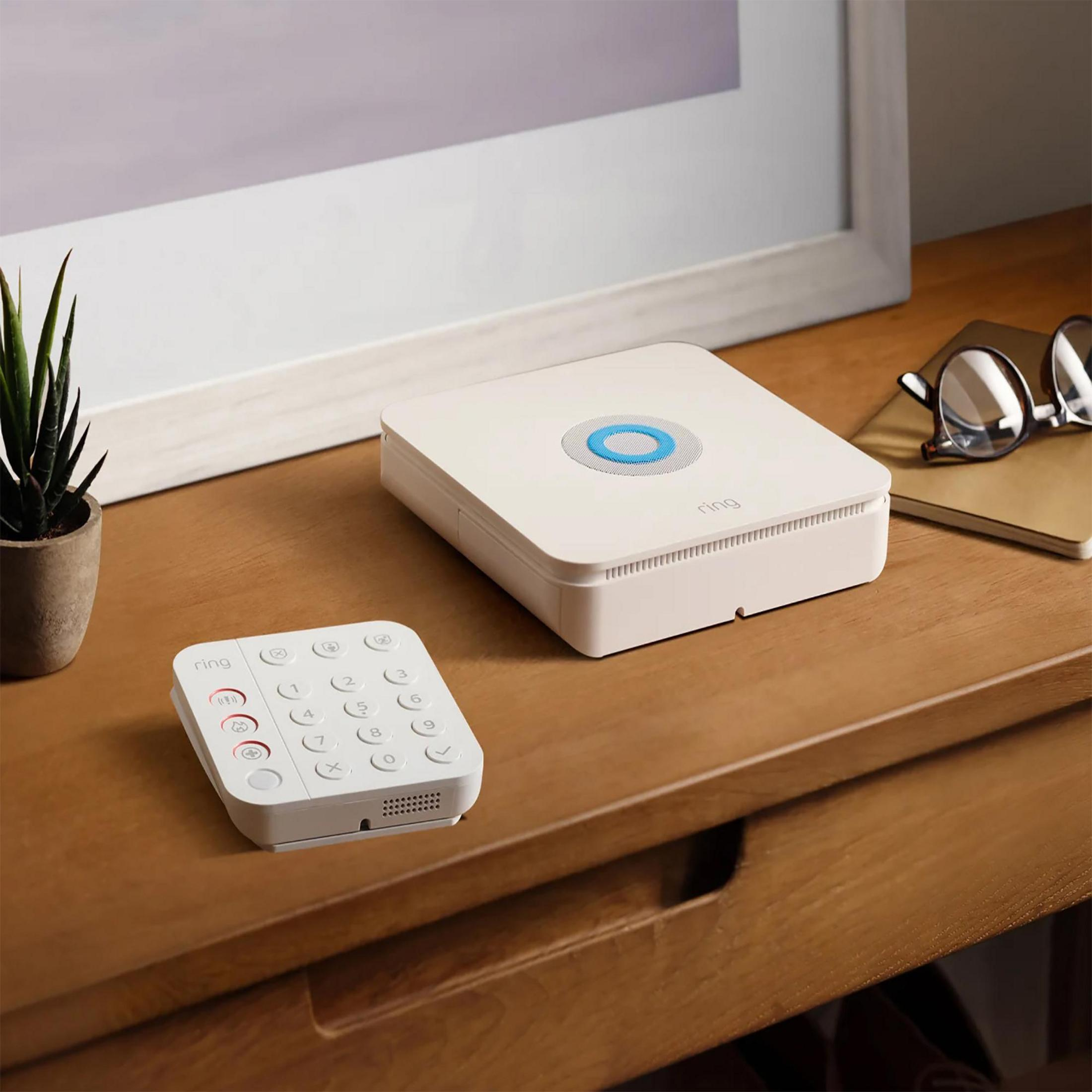 Un teclado y estación base de Ring Alarm blancos sobre una mesa de madera.