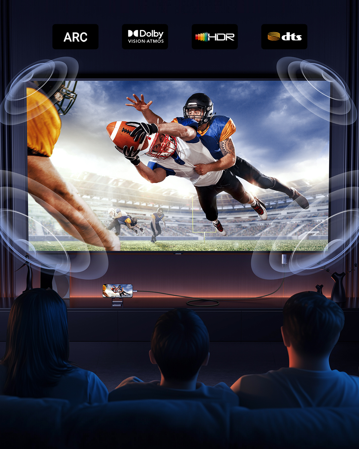 İki kişi akıllı telefonla TV'de Amerikan futbolu maçı izliyor. ARC, Dolby Vision, HDR, DTS logoları.
