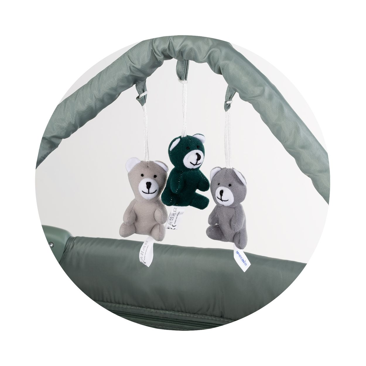 Drei Teddybären-Anhänger hängen an einem Spielbogen über einer grünen Unterlage.
