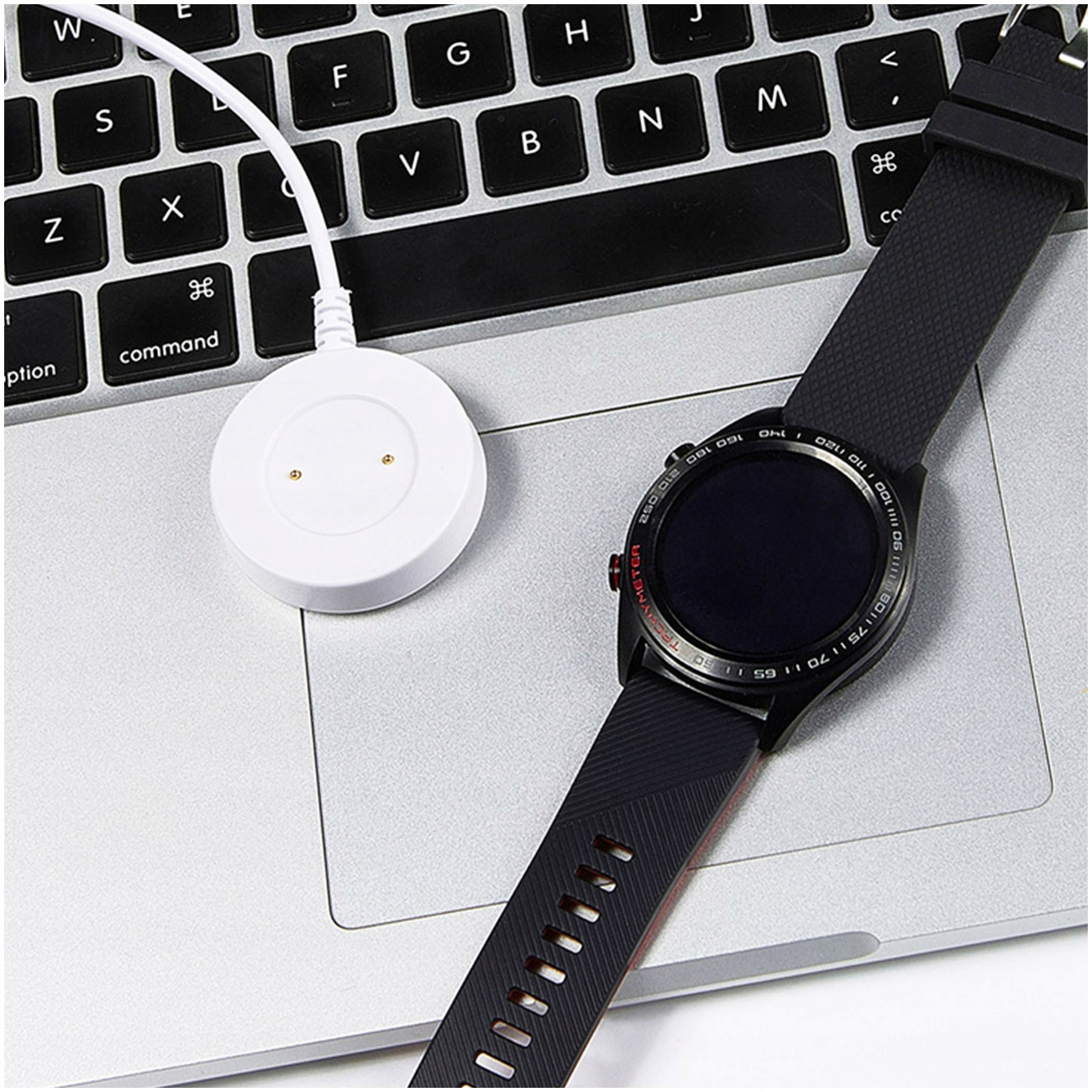 Smartwatch z czarną bransoletą i białą ładowarką na klawiaturze.