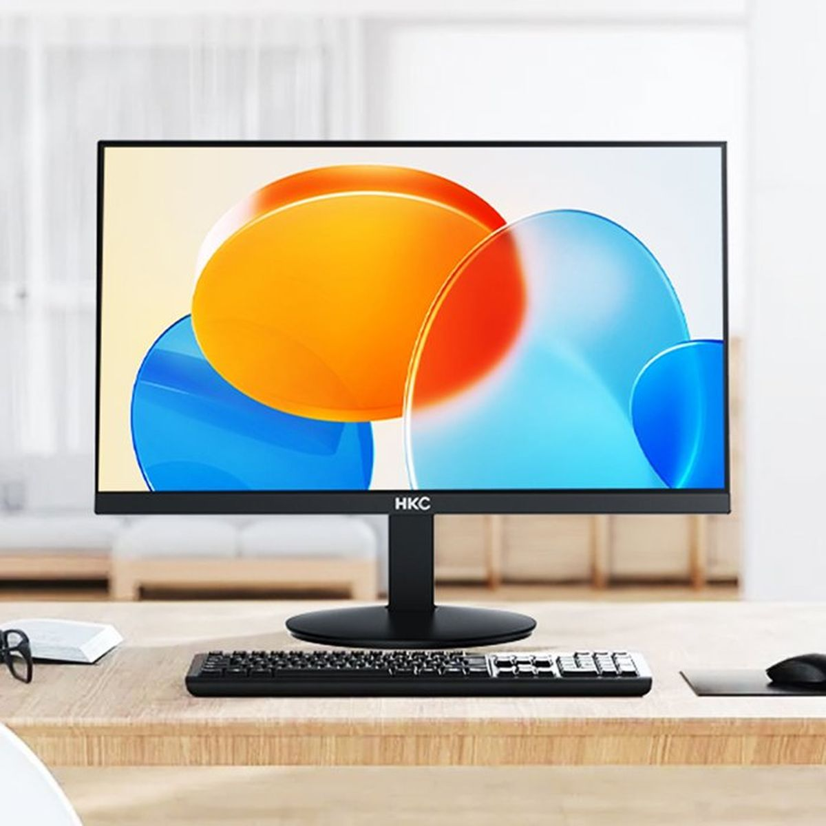 Un monitor HKC nero mostra forme astratte colorate. Tastiera e mouse davanti.