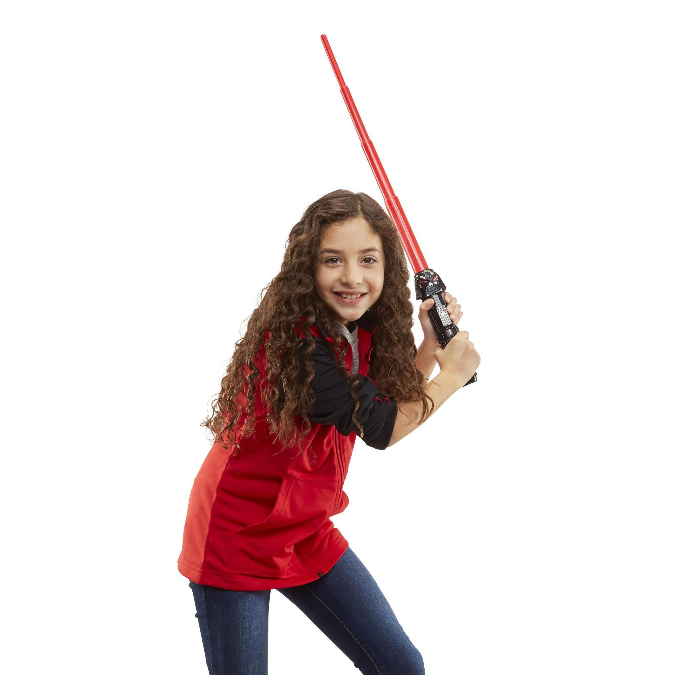 Bambina con capelli ricci tiene spada laser rossa, indossa gilet e jeans.