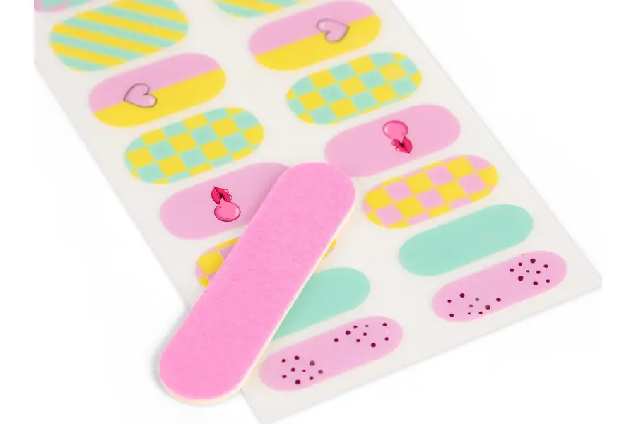 Pegatinas para uñas con patrones como cuadros, rayas, corazones y puntos, con lima rosa.